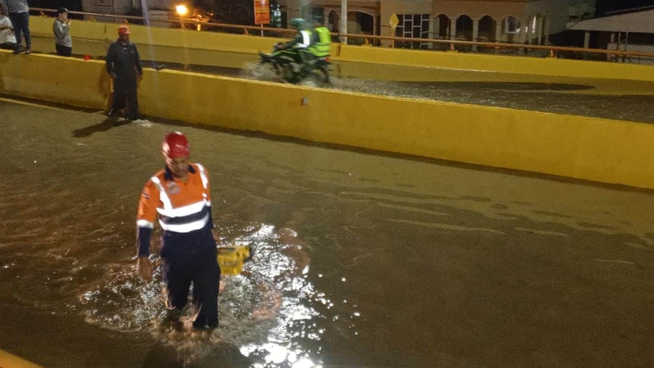 Un obrero camina por el elevado de la avenida Monumental en Santiago en momentos en que estaba inundado.