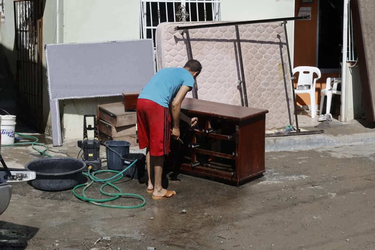 Un hombre de San José de Ocoa intenta rescatar sus pertenencias, entre ellas un gavetero arrastrado por las lluvias de Melissa.