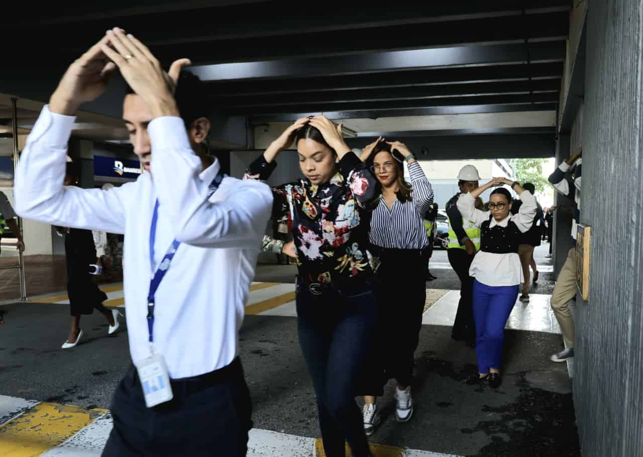 Personas que laboran en el edificio gubernamental Juan Pablo Duarte, conocido como El Huacal, abandonan sus oficinas durante el simulacro por terremoto, este miércoles 5 de noviembre. 