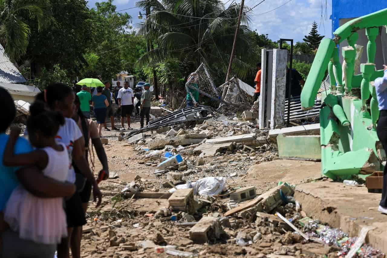 Residentes caminan entre calle en mal estado y por los escombros tras la explosión.