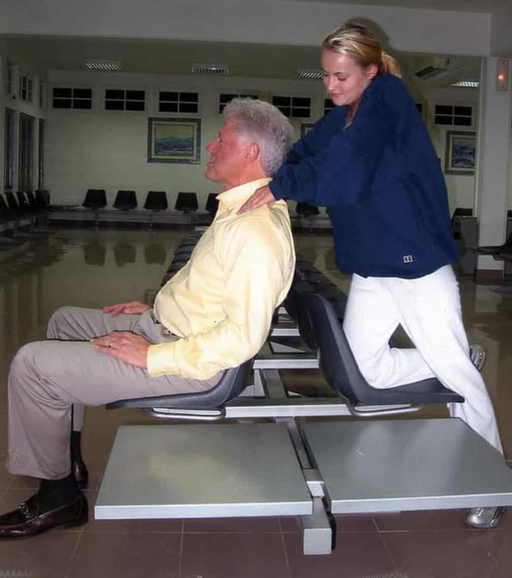  Clinton recibe un masaje de cuello y hombros de la víctima de Epstein Chauntae Davies durante una escala en 2002.