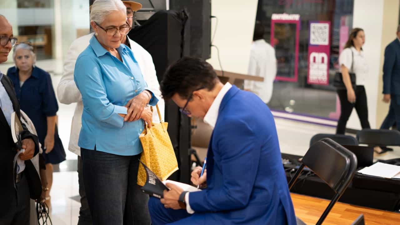 Miguel Braho firma autógrafos y dedica mensajes personalizados a los asistentes luego de su presentación en Acrópolis Business Mall.
