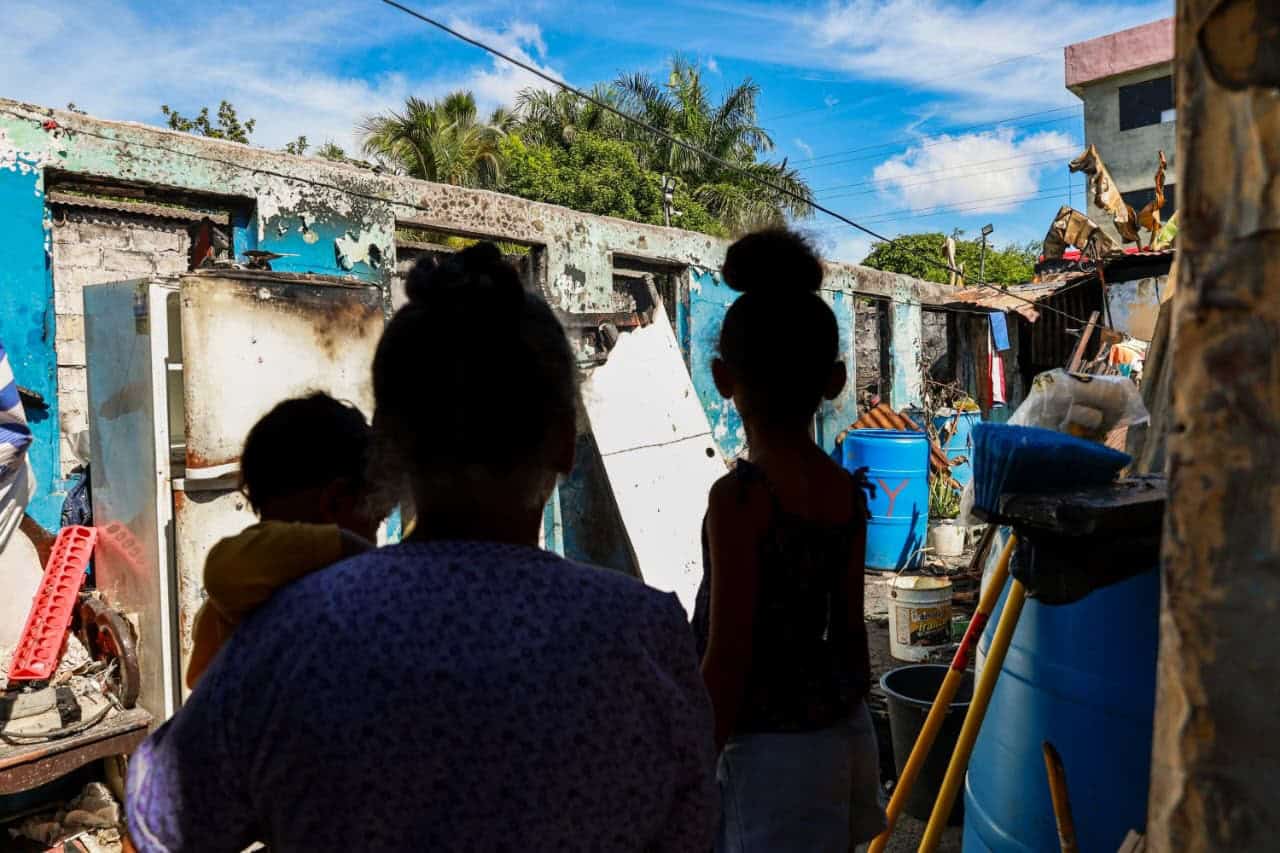 Parientes de la anciana observan los restos de la vivienda casi consumida por las llamas.