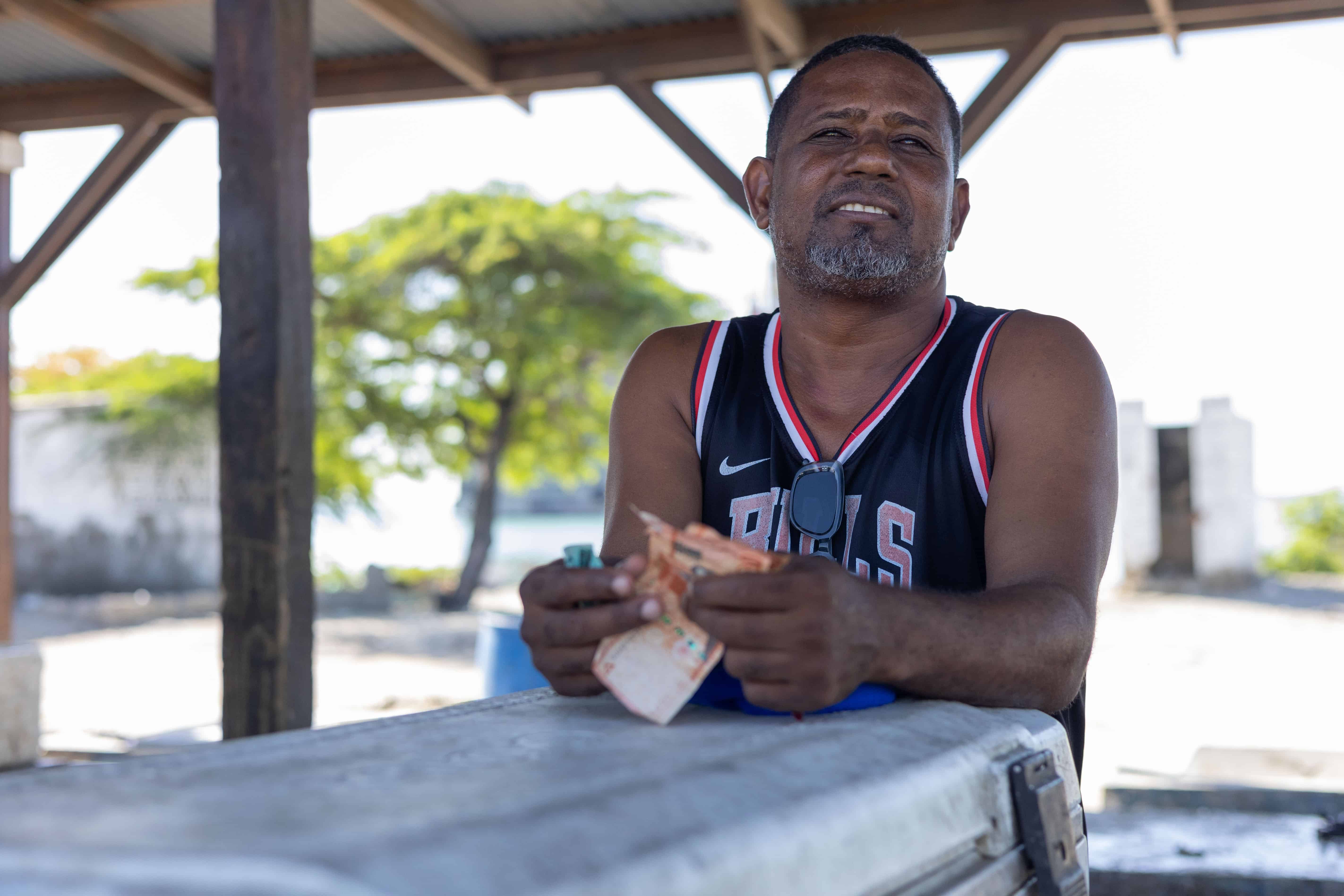 Cristian González, vendedor en la playa Los Negros, afirma que el humo de las barcazas "se mete a las casas" y ha alejado a los clientes, afectando su sustento diario.