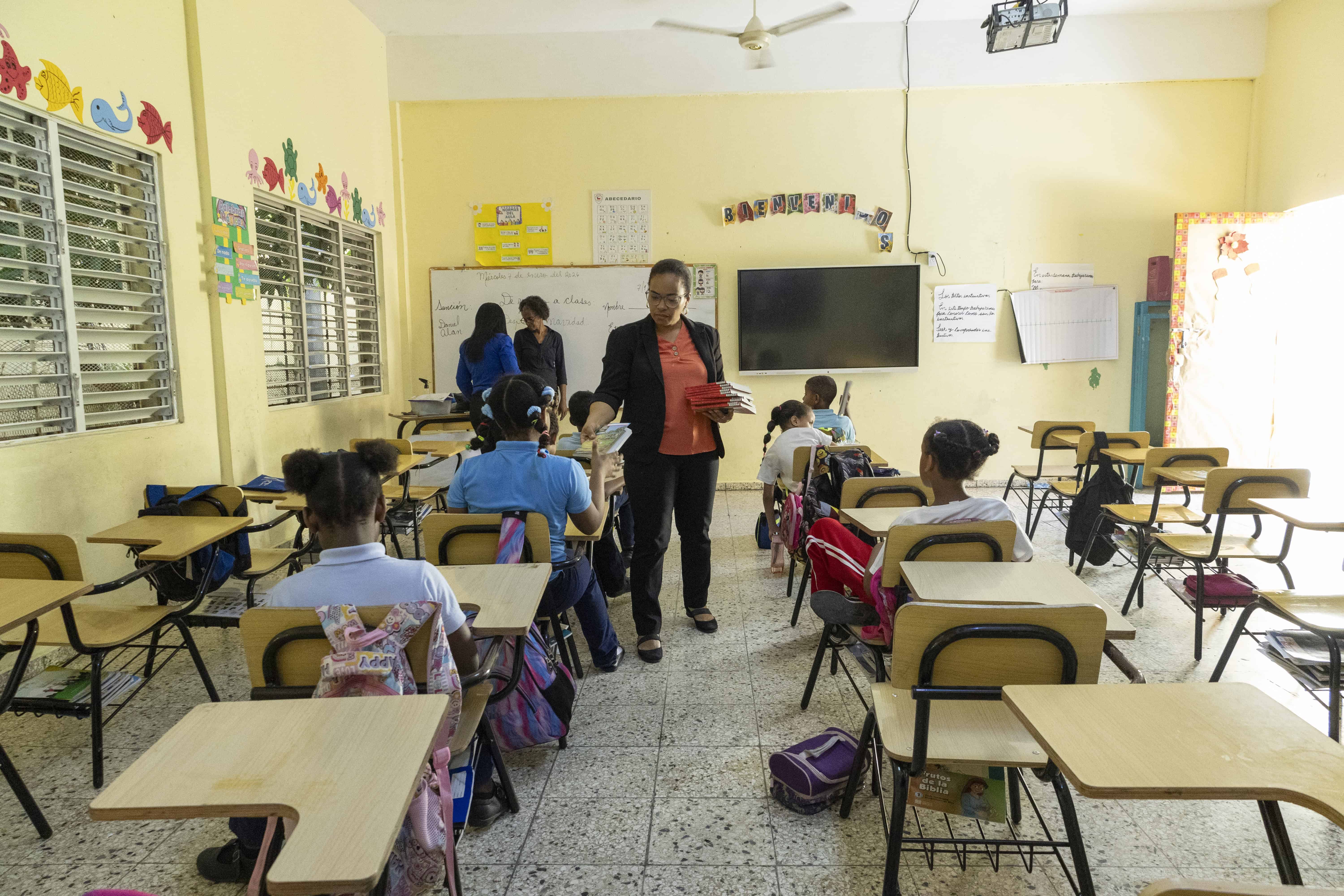 Una docente entrega libros a los estudiantes durante una actividad de lectura en la Escuela República de Chile.