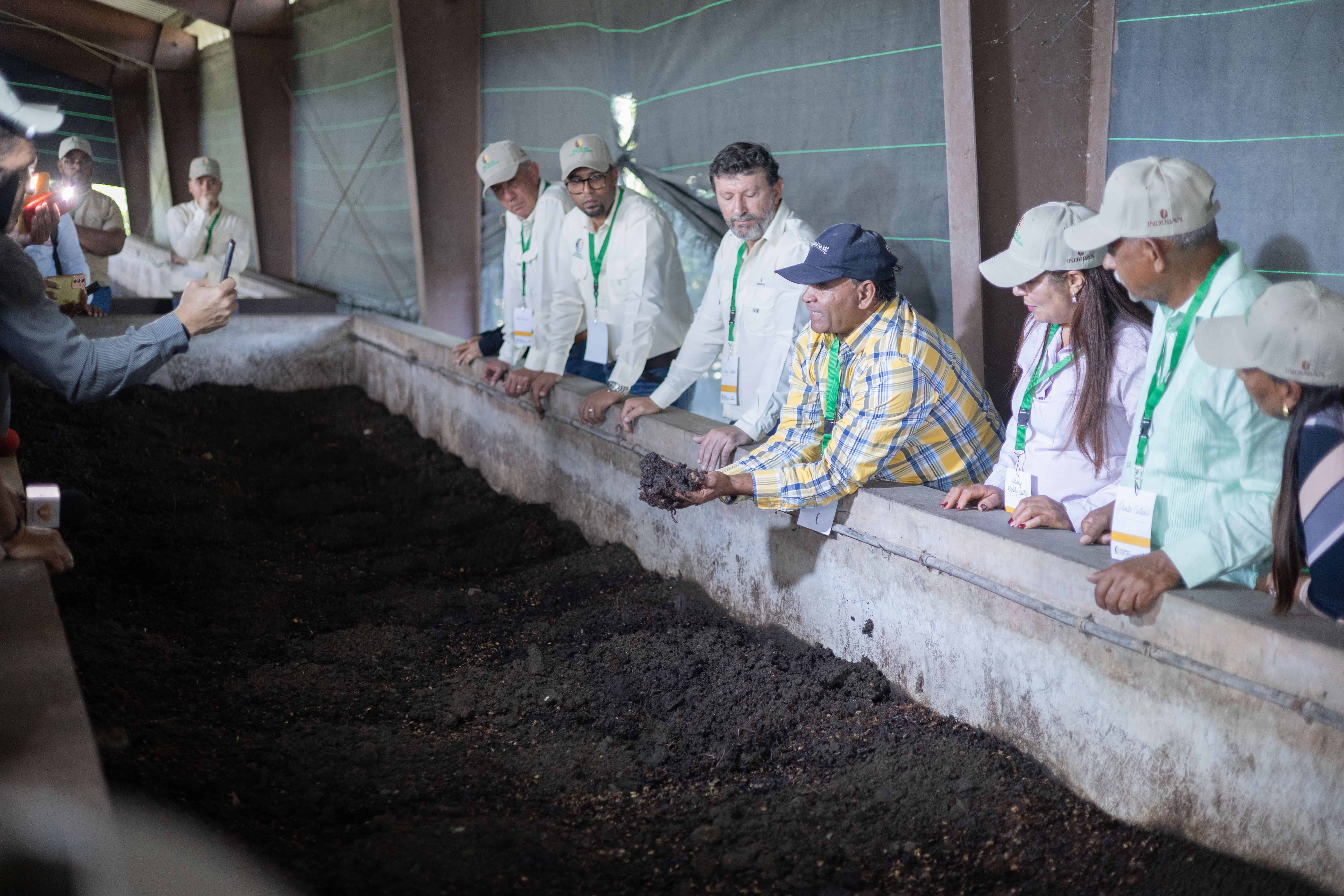 Un empleado de Induban (centro) sostiene con las manos el humus, un compostaje natural creado con lombrices y residuos org&aacute;nicos. Este abono org&aacute;nico se utiliza dentro de la finca de Induban para potenciar el crecimiento de las plantas.