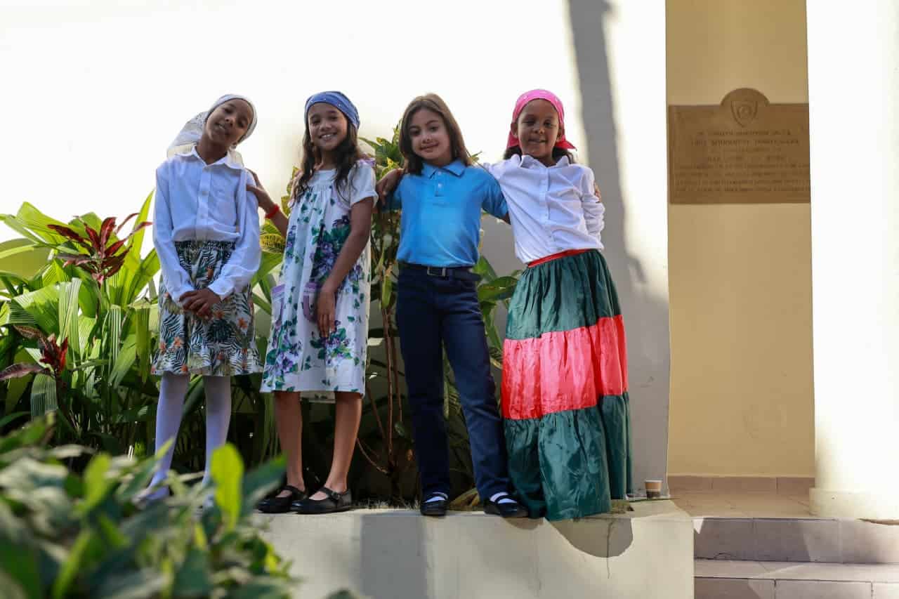 Un grupo de estudiantes posa utilizando trajes típicos tradicionales frente al palacio municipal de San José de Ocoa.