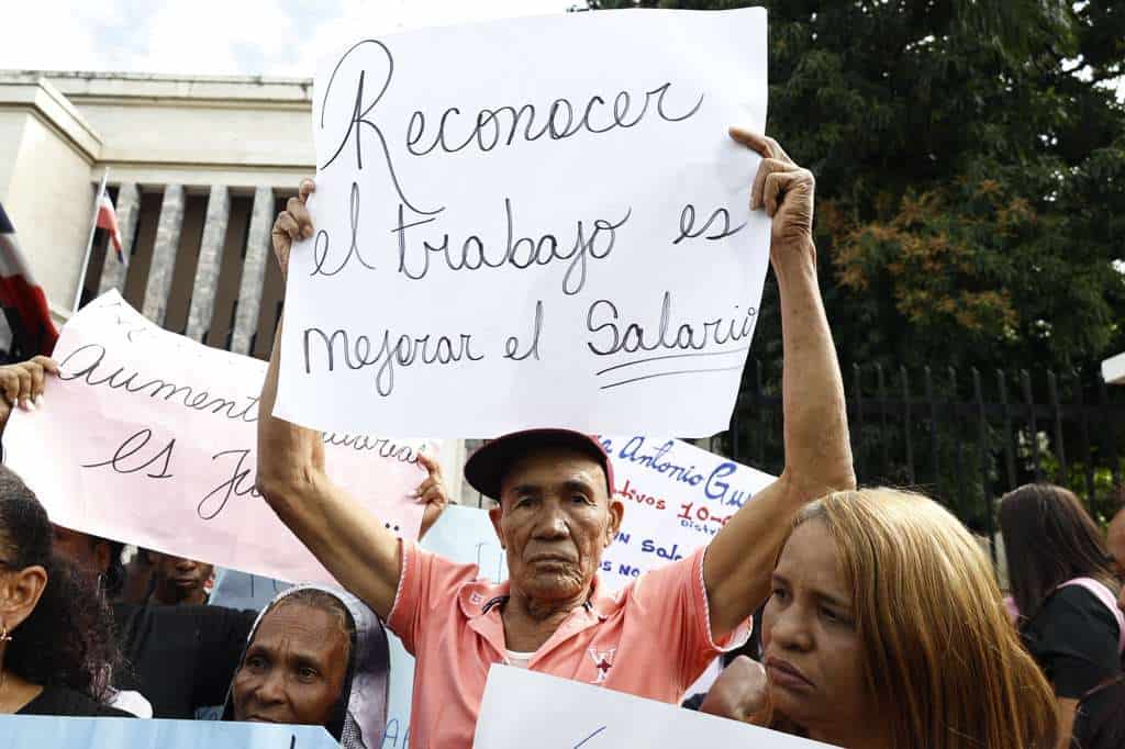 Conserjes, auxiliares y personal de servicios exhiben carteles con mensajes exigiendo salarios dignos durante la manifestaci&oacute;n este 9 de febrero de 2026.