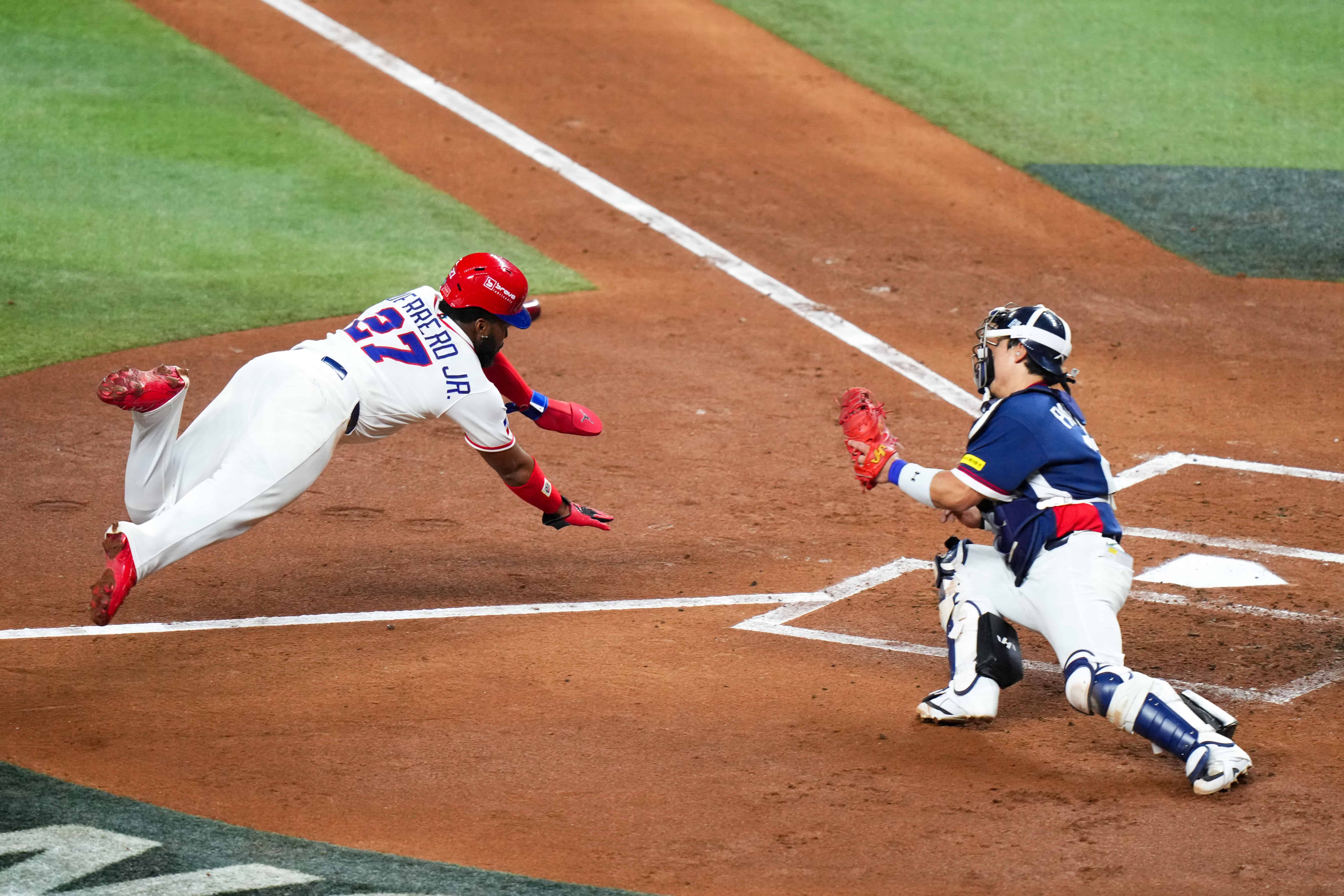Vladimir Guerrero Jr. se apresta a barrerse en el plato durante la segunda entrada del encuentro ante Corea del Sur.