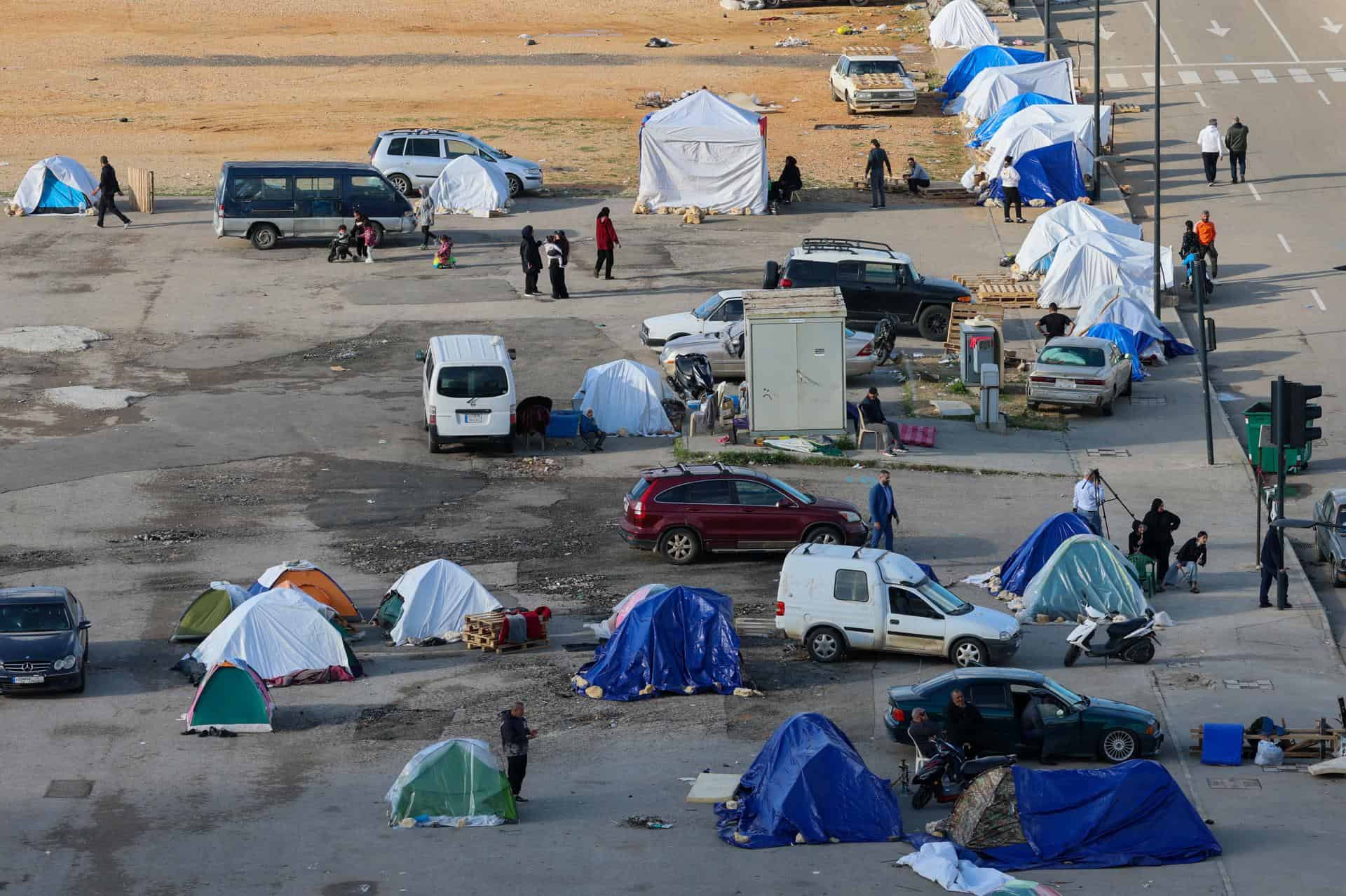 Parte de los desplazados con sus pertenencias, se sientan junto a tiendas de campa&ntilde;a mientras huyen de sus hogares en el sur del L&iacute;bano y los suburbios del sur de Beirut tras los ataques a&eacute;reos israel&iacute;es en Beirut, L&iacute;bano, el 16 de marzo de 2026.