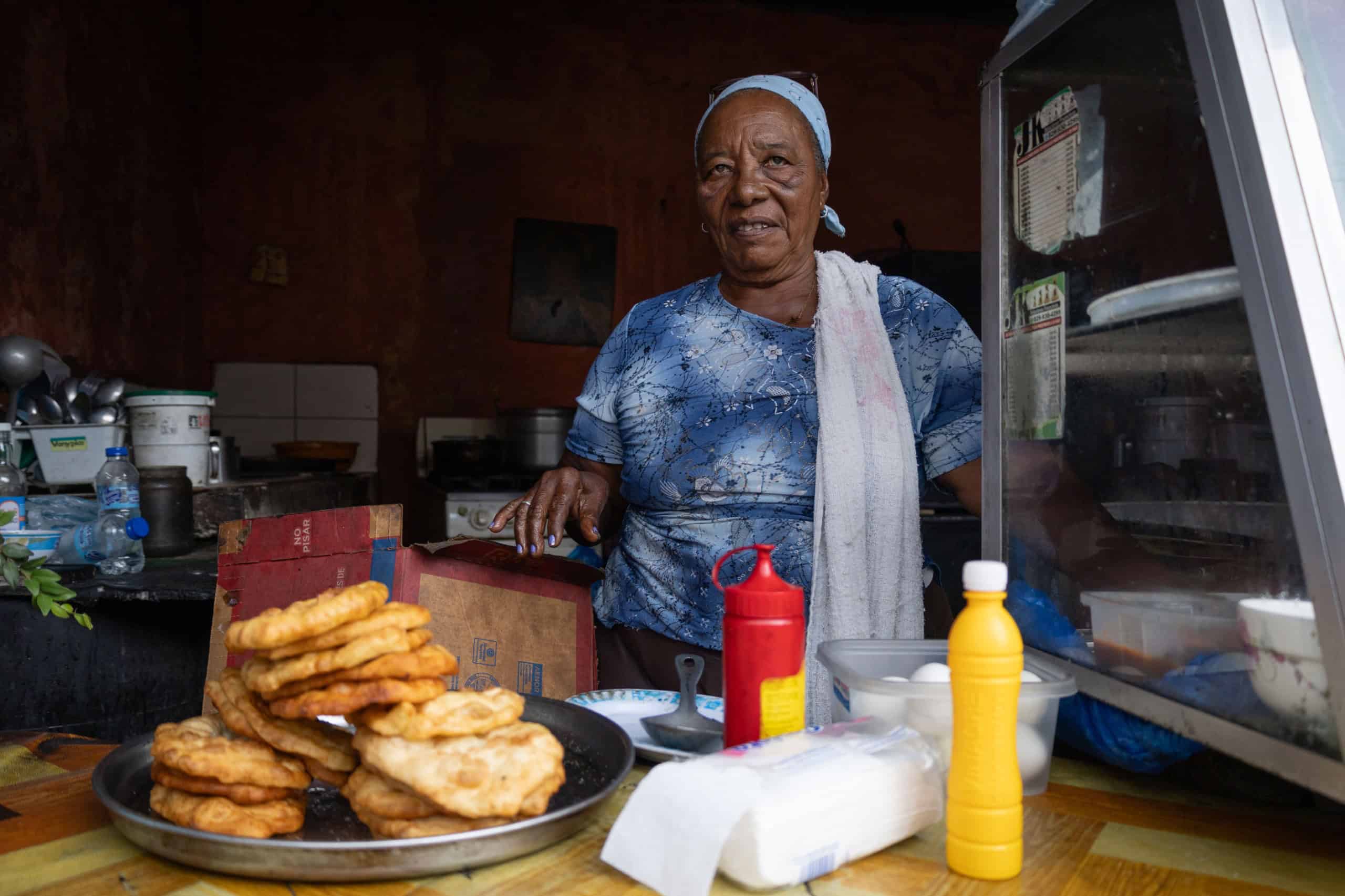 Miledy Trinidad, quien vende yaniqueques y otros alimentos, observa la rutina diaria en la zona del almacén del Minerd.