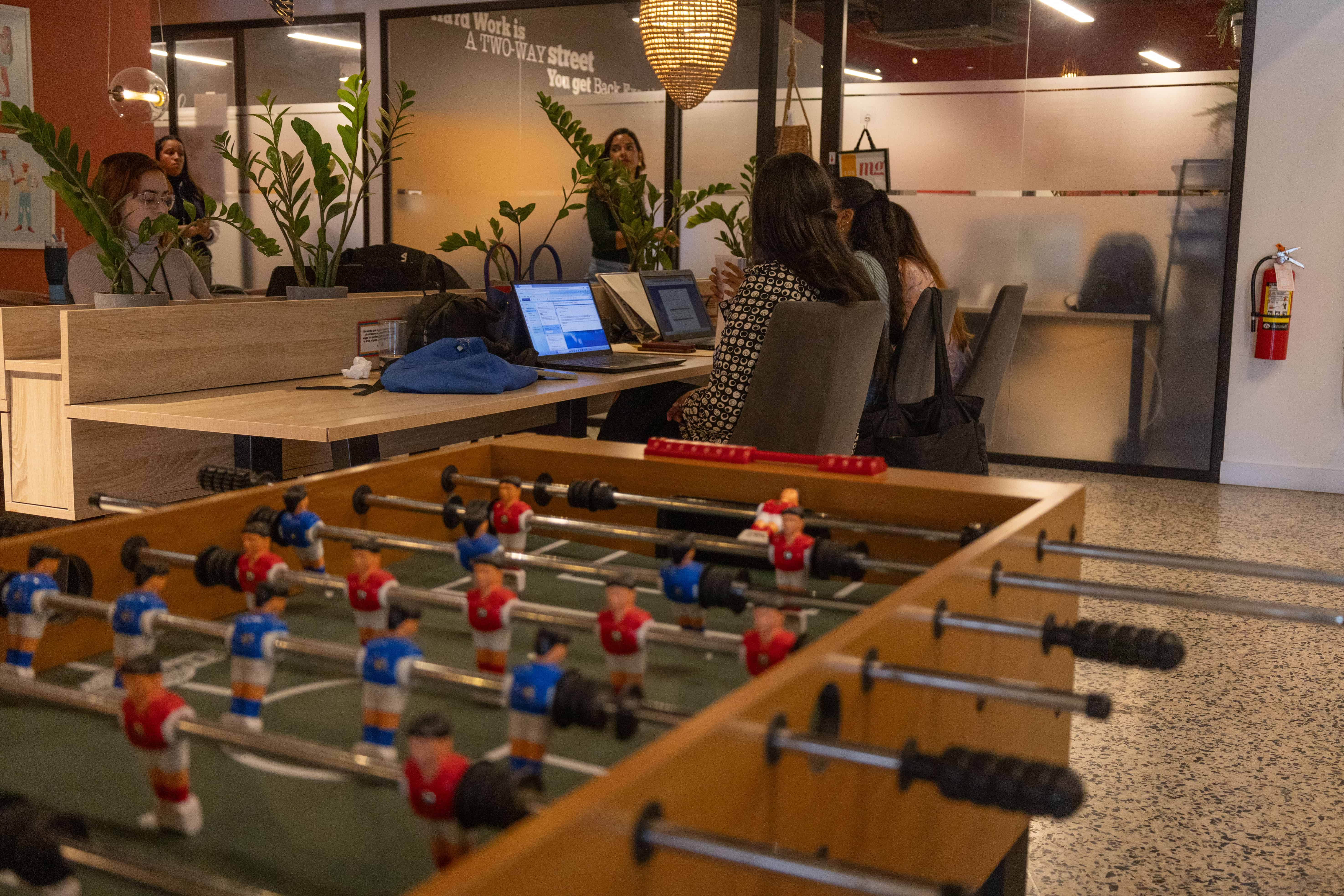 Usuarias trabajan frente a una mesa de futbolito en Spirit Coworking.