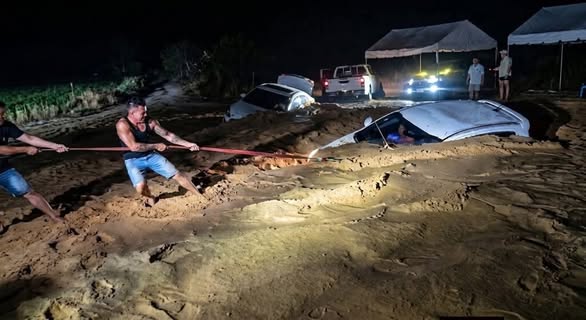 Hombres auxilian a los vehículos que fueron arrastrados anoche.