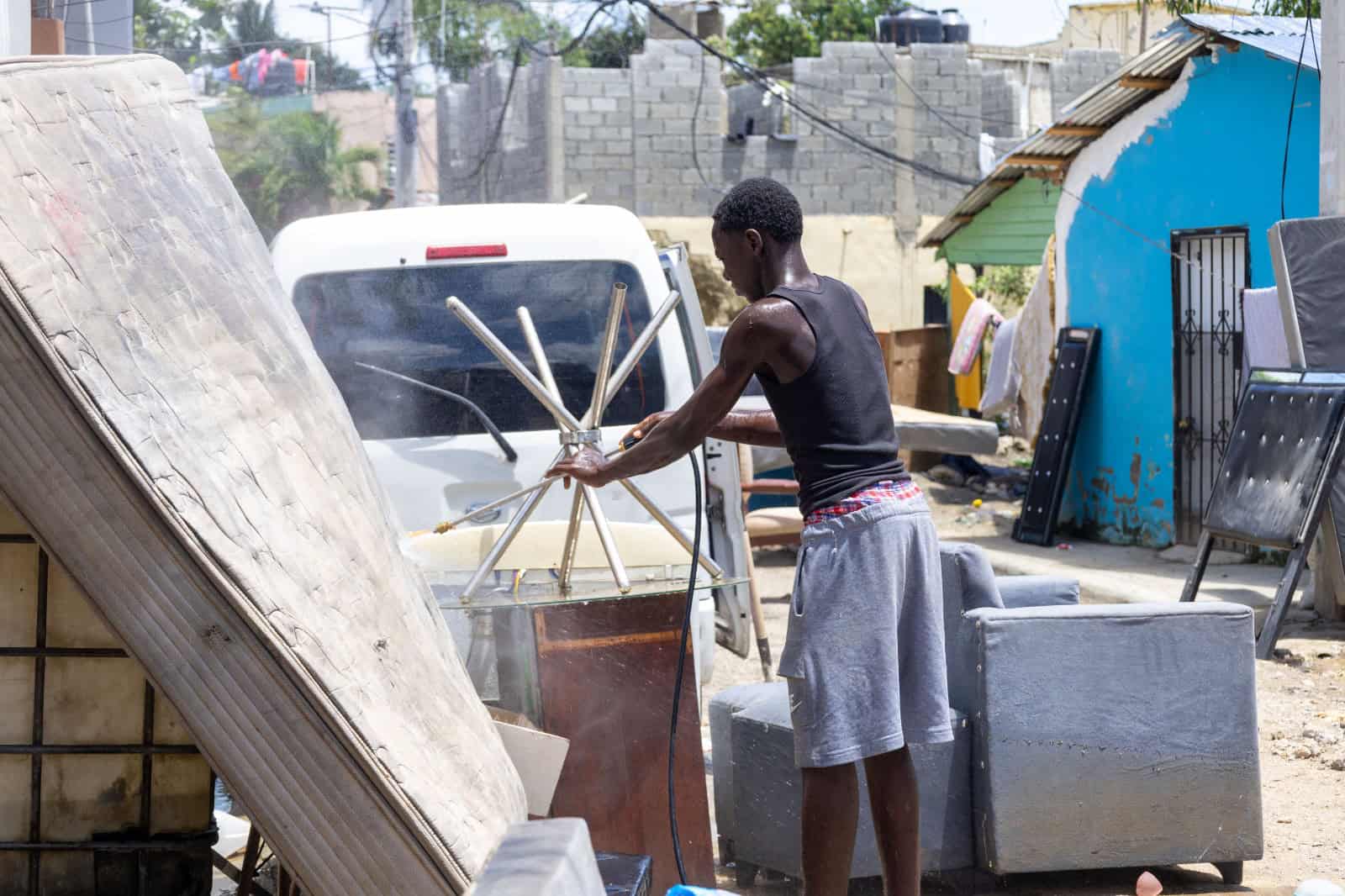 Un joven lava en plena calle un colchón afectado por las lluvias, en un intento por recuperar algo de lo perdido tras la inundación.