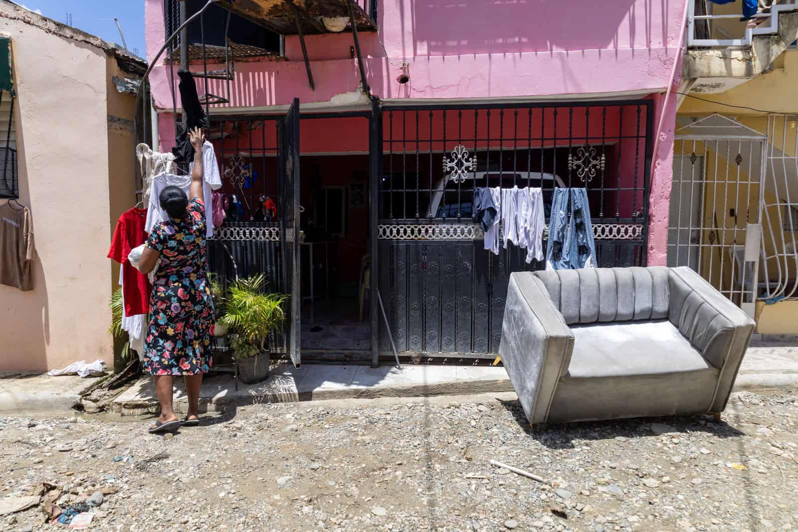 Isabel De la Rosa tiende al sol parte de la ropa que logró rescatar, mientras intenta secar un mueble frente a su vivienda tras la inundación en Villa María, Pantoja.