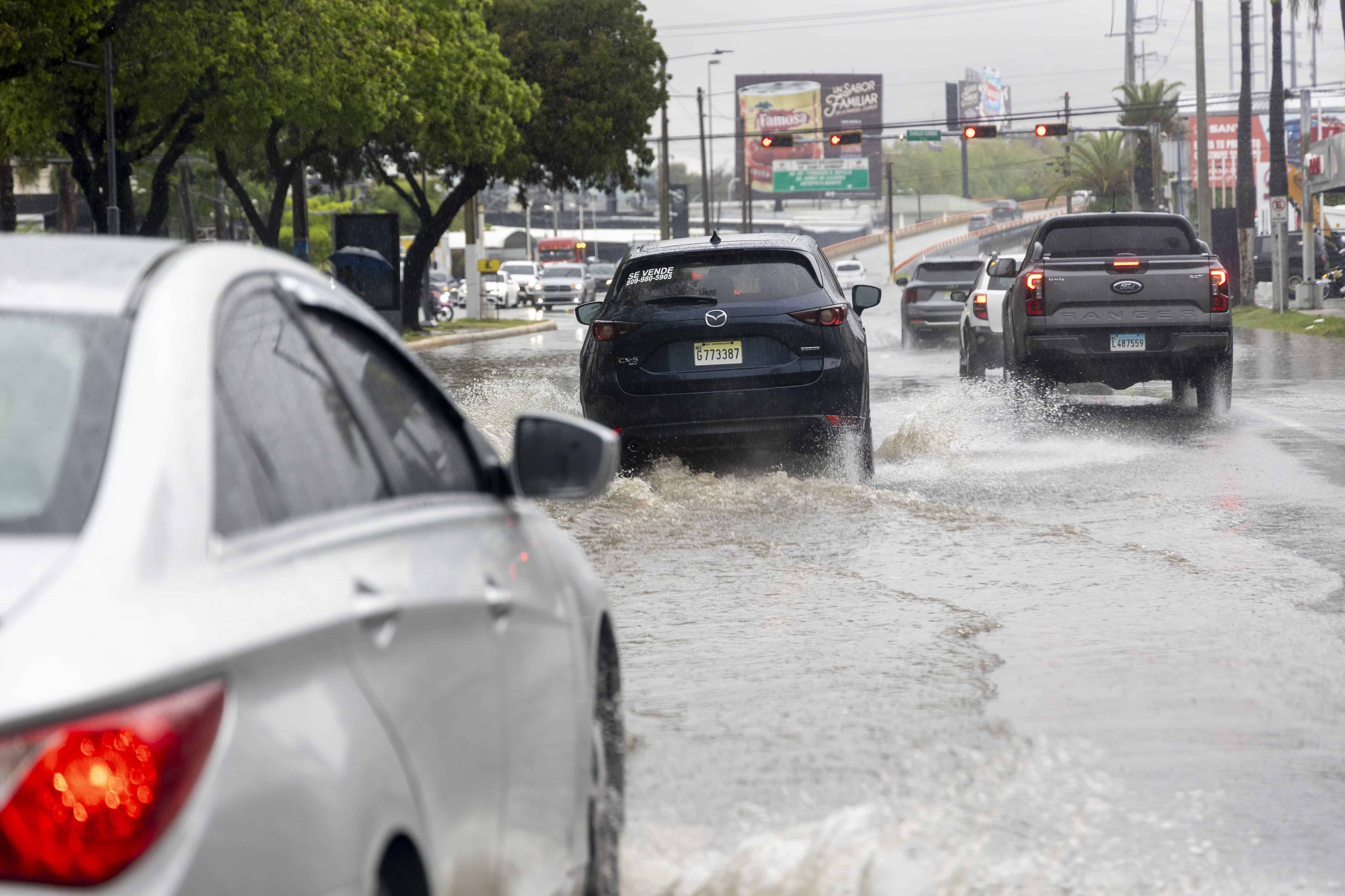 Carros transitando por una calle del Gran Santo Domingo en un día de lluvia.