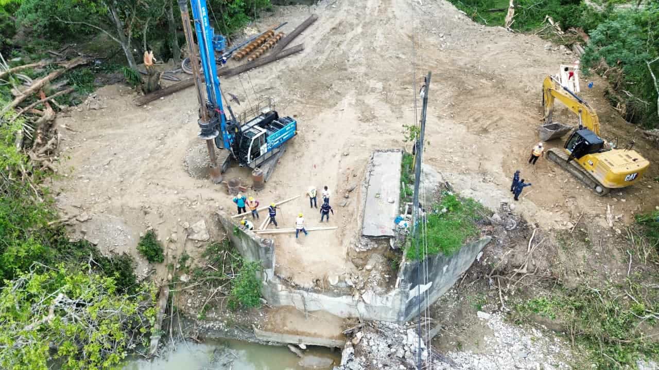 La reconstrucción del puente, con maquinaria pesada y equipos de ingenieros trabajando en la zona.