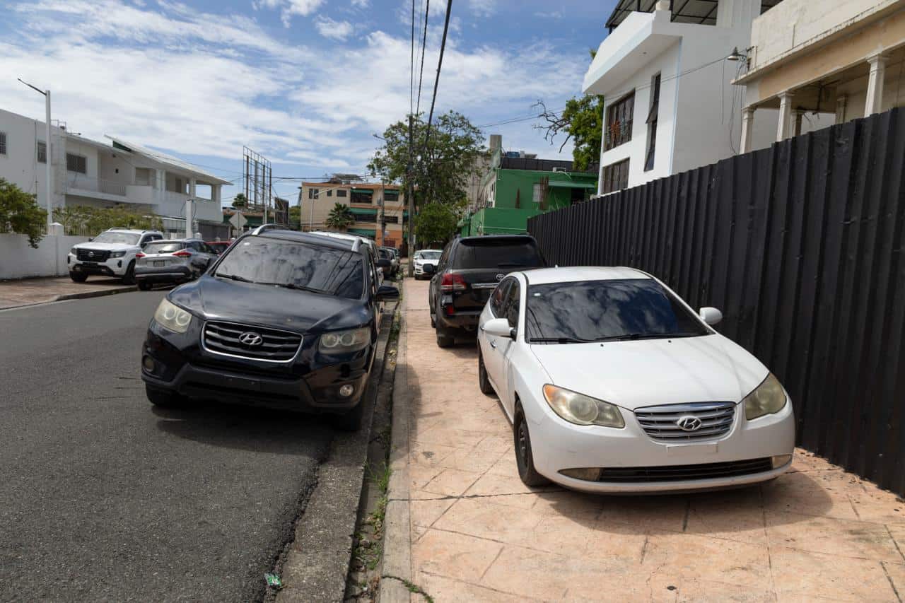 Veh&iacute;culos estacionados en doble fila entre la calle y la acera en Gascue.