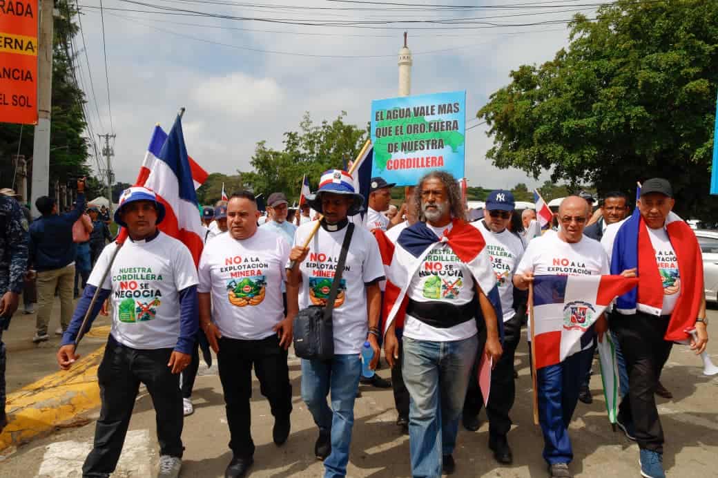 El sacerdote Ram&oacute;n Ramos, junto a otros participantes, lidera la marcha con banderas en manos, pidiendo la protecci&oacute;n de la Cordillera Septentrional frente a la miner&iacute;a.