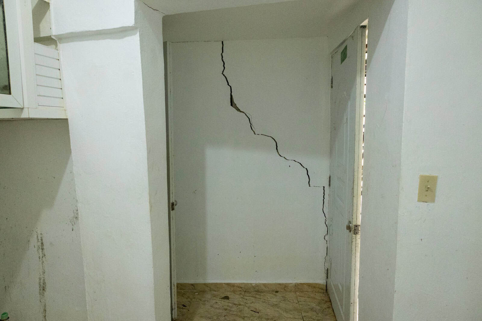 Interior de uno de los apartamentos, donde las grietas y daños son visibles en paredes y techo.
