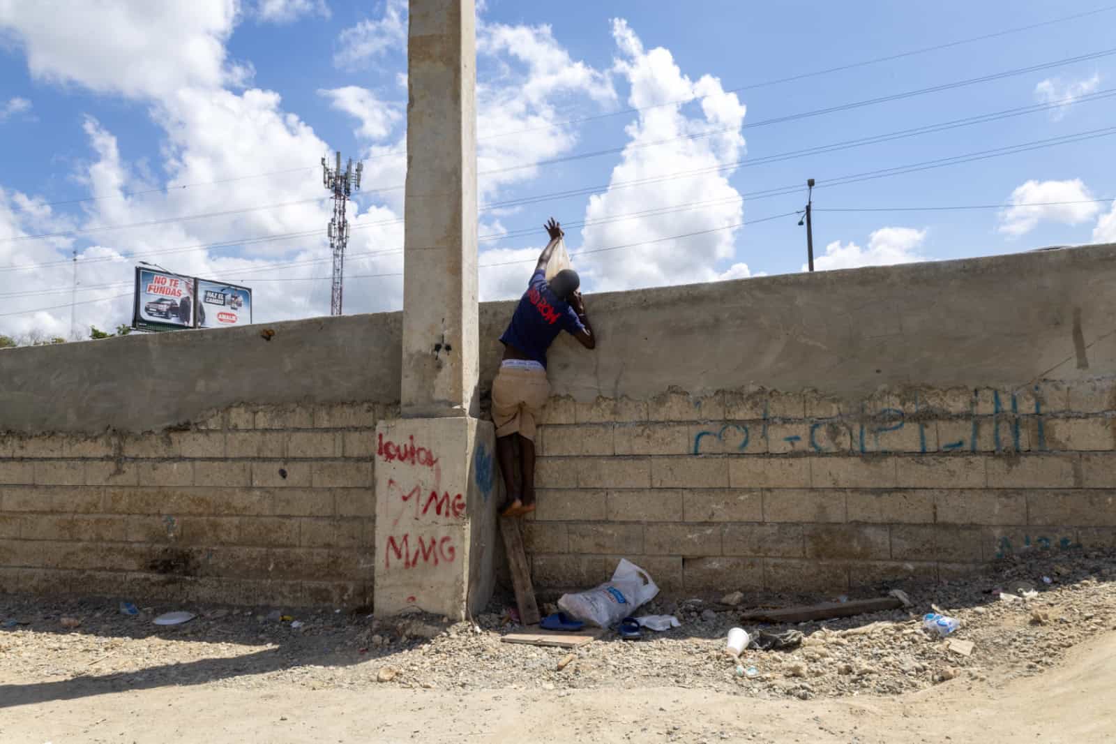 Ni&ntilde;o intenta subir a la acera con fundas de basura ante la falta de accesos adecuados.
