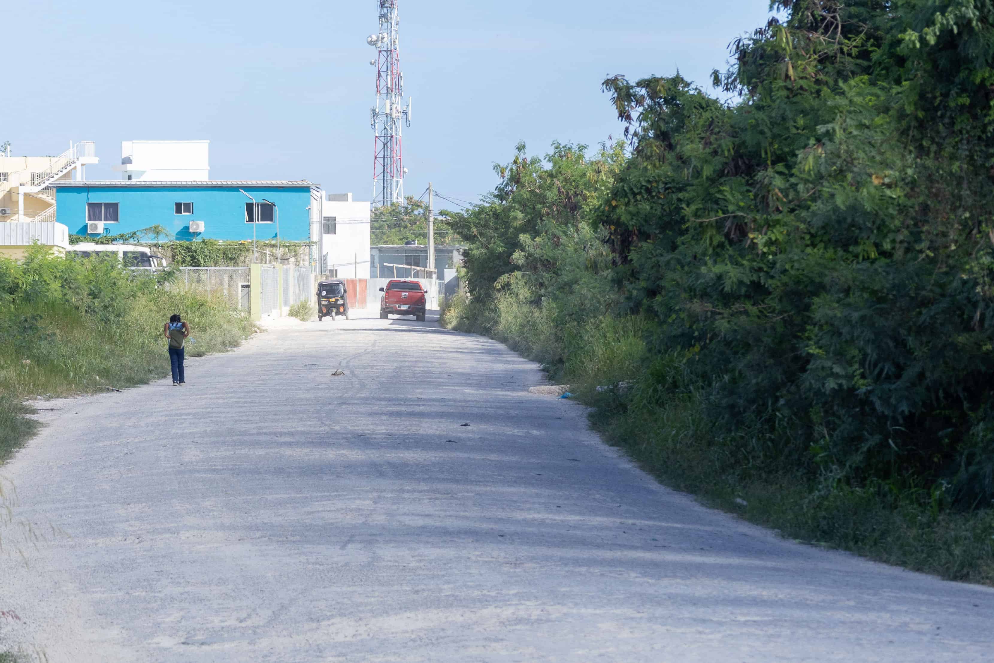 Una ni&ntilde;a caminando a lo lejos en una v&iacute;a polvorienta que conecta con la calle Domingo Ma&iacute;z en Ver&oacute;n-Punta Cana.