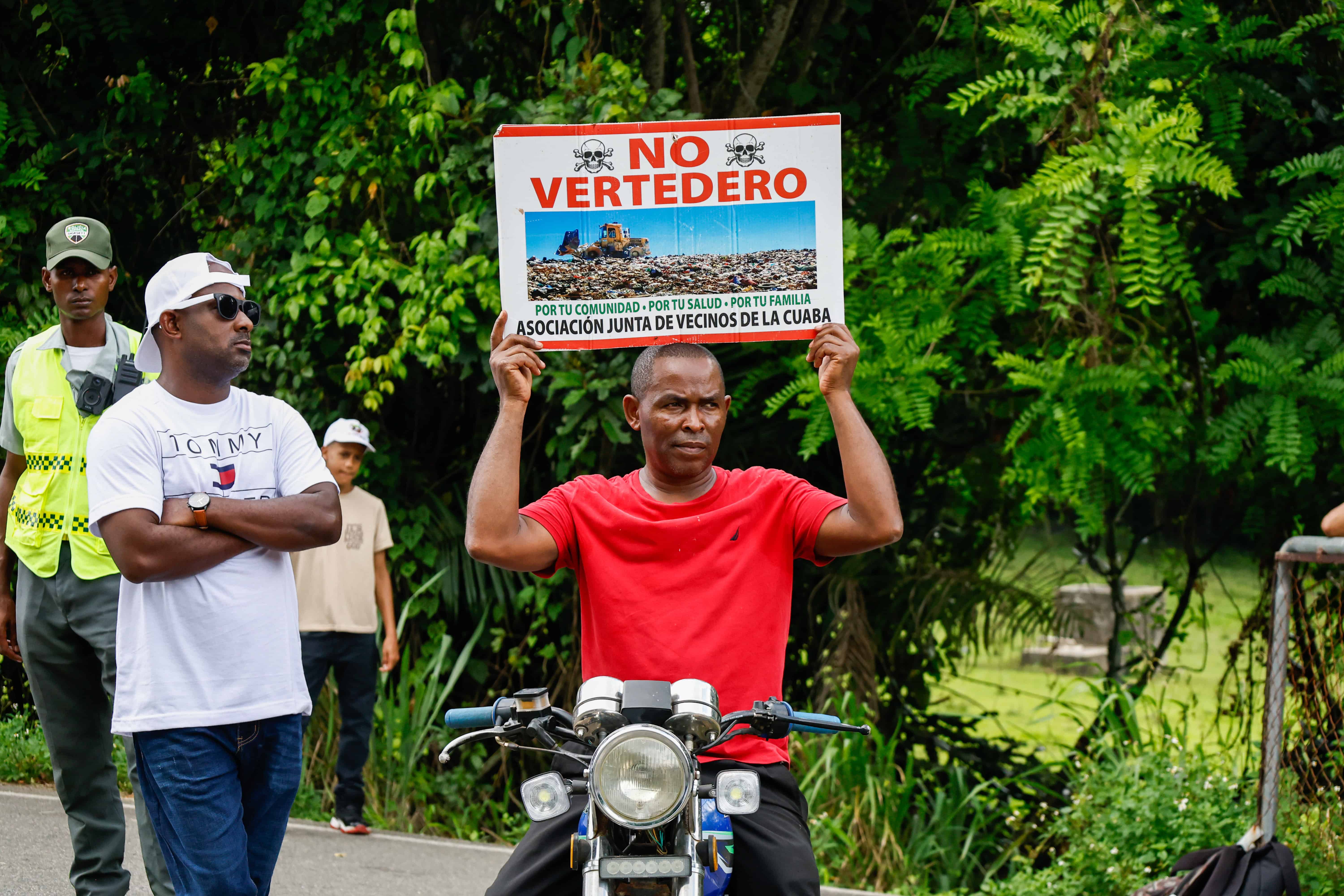 Un hombre en una motocicleta con una pancarta de rechazo al proyecto.