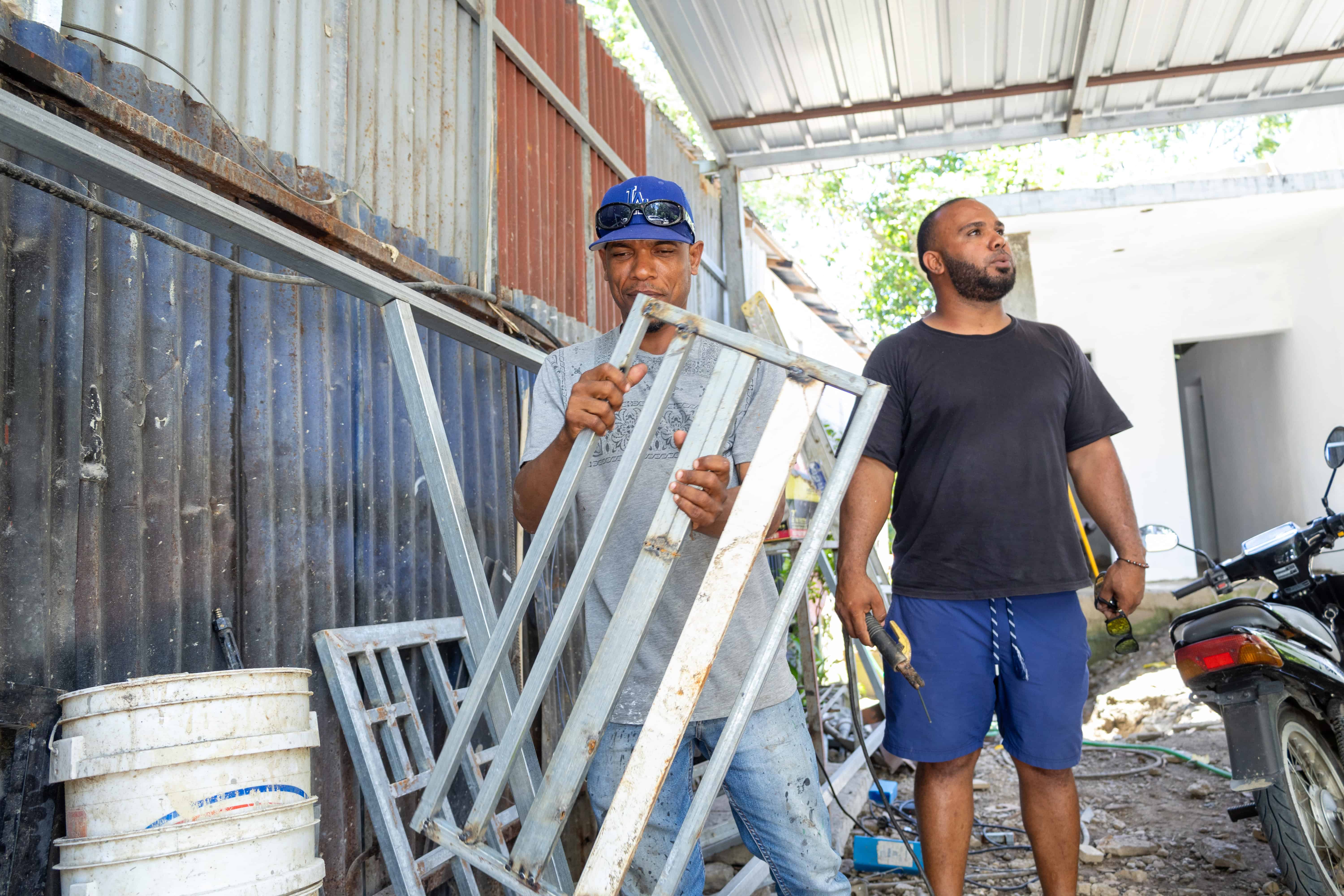 José, exinterno de la cárcel de Salcedo levanta un hierro en el taller de Jeury, el propietario y tambien antiguo recluso. Ambos aprendieron electricidad y herrería.