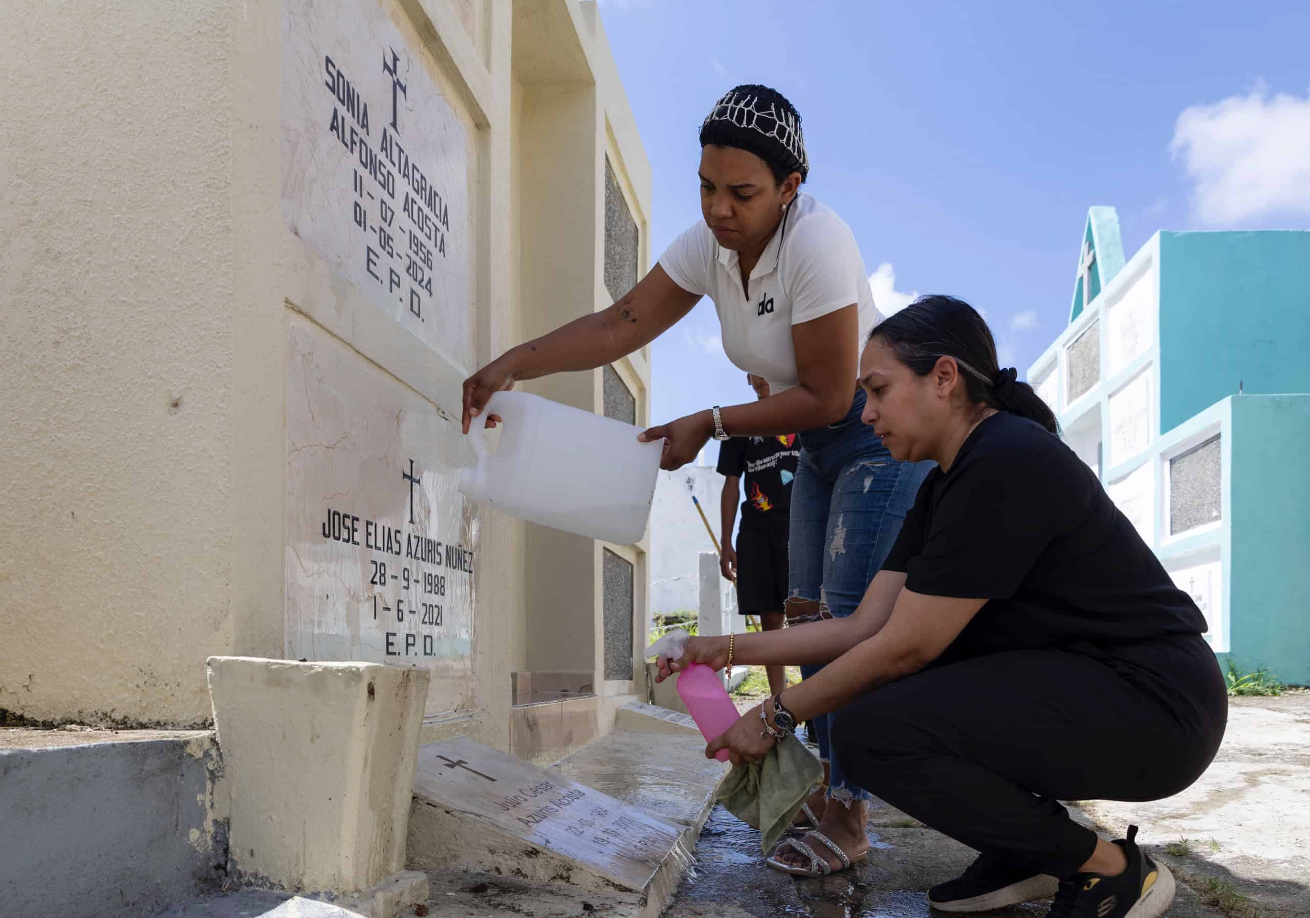 Visitantes limpian cuidadosamente la tumba de su madre.