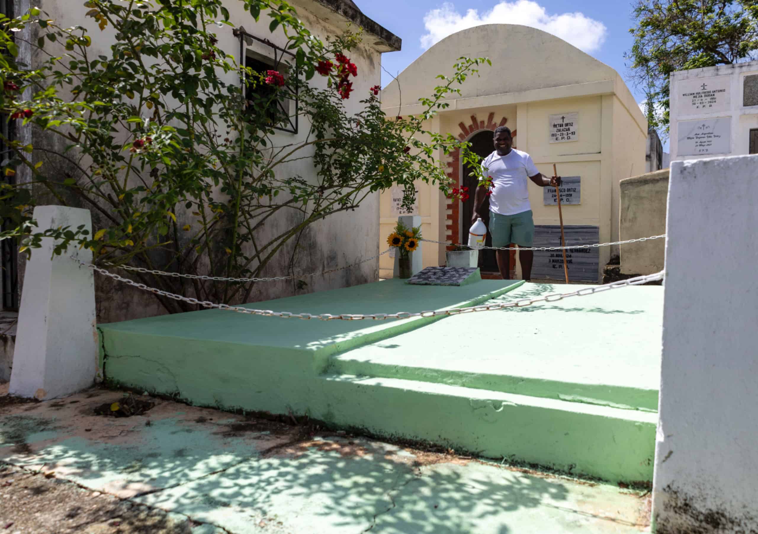 Un hombre concluye las labores de limpieza en la tumba de un familiar durante su visita al cementerio.
