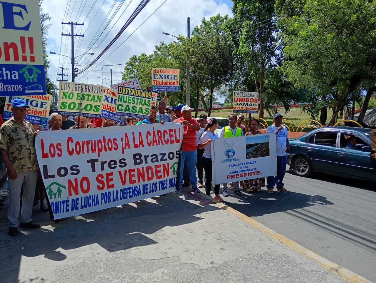 Los residentes de los Tres Brazos portan pancartas en las que destacan sus demandas.