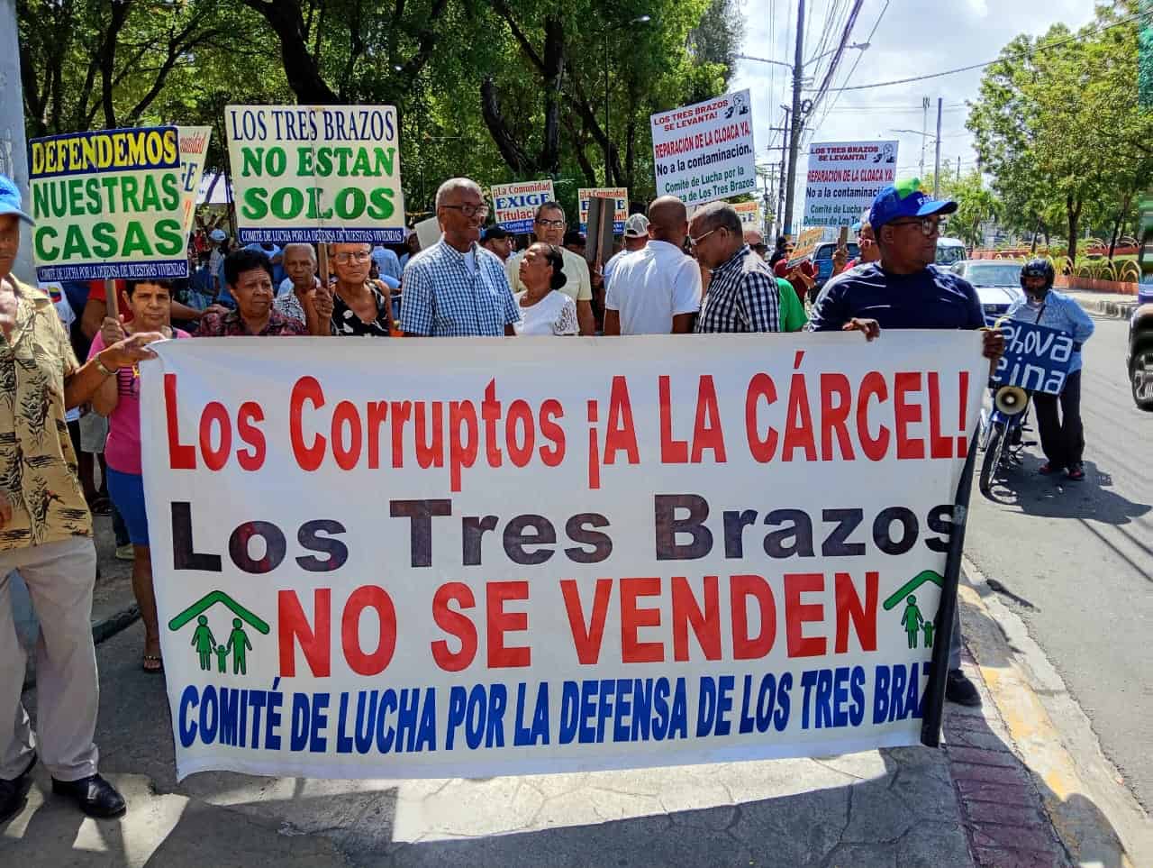 Los residentes de los Tres Brazos portan pancartas en las que destacan sus demandas.