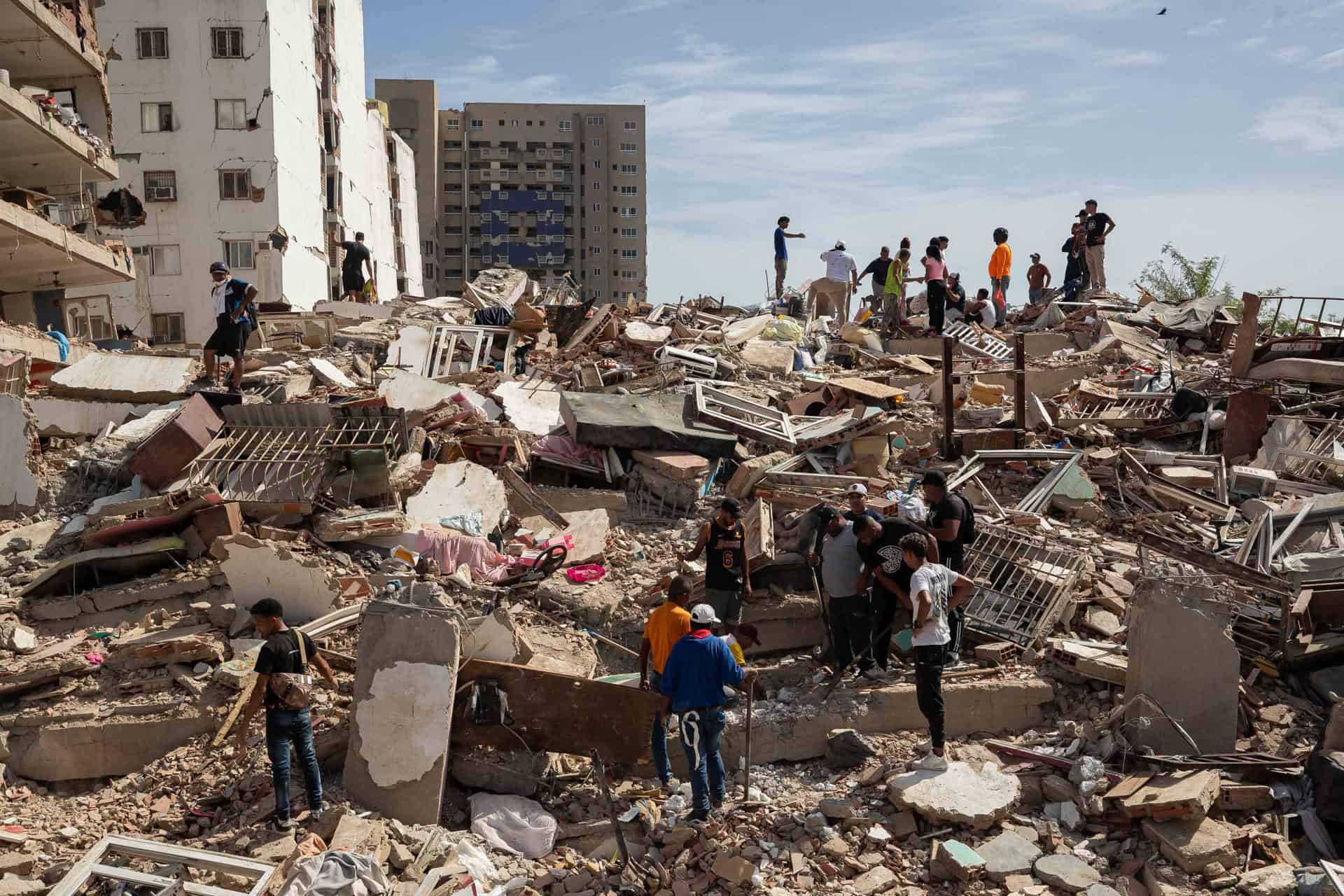 Personas caminan entre escombros de edificios afectado por terremotos este jueves, en Catia La Mar (Venezuela).