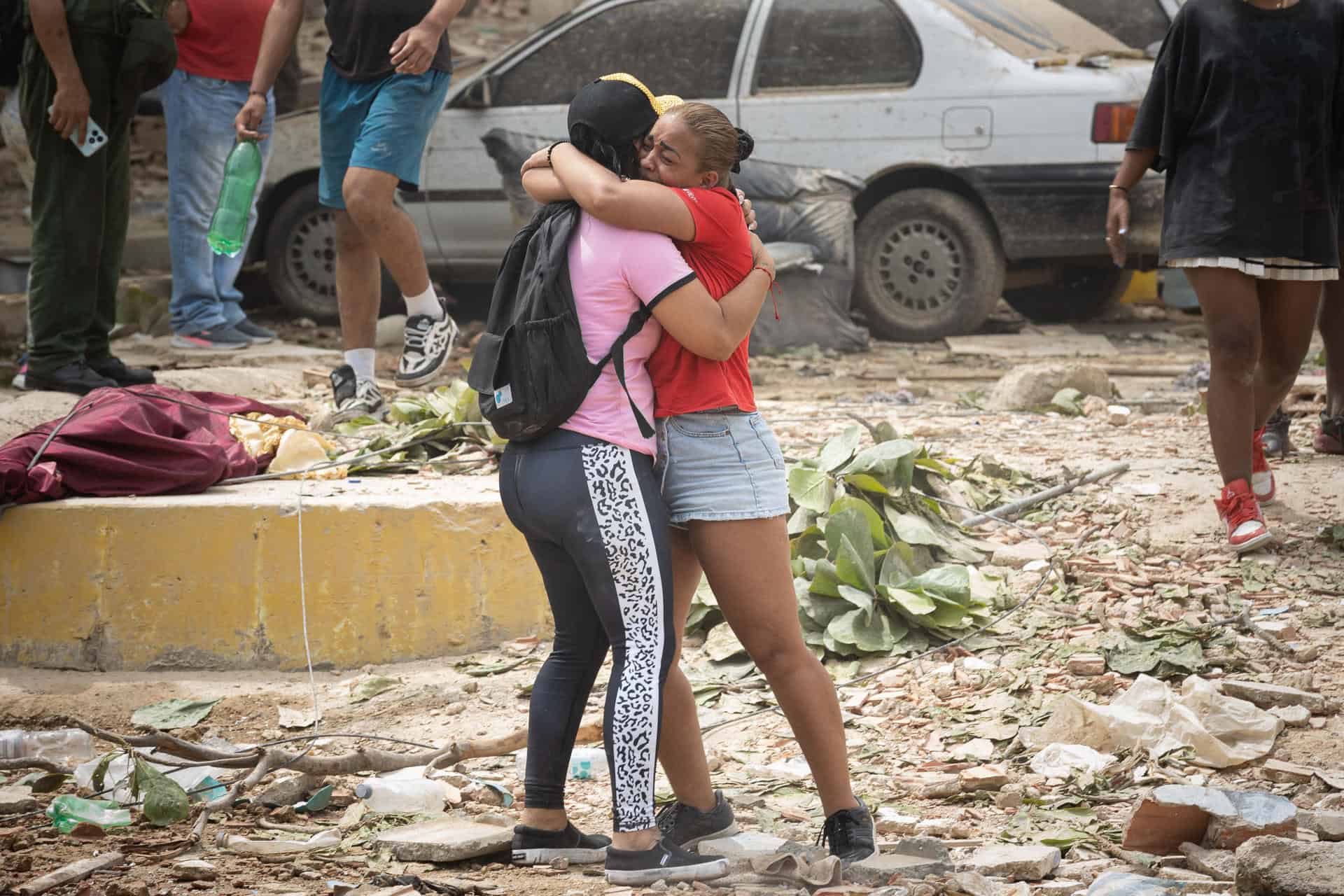 Personas lloran frente a escombros de edificios afectados por terremotos este jueves, en La Guaira (Venezuela). 