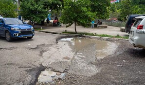 Entre hoyos y agua acumulada: as&iacute; transitan conductores y peatones por calles del Gran Santo Domingo