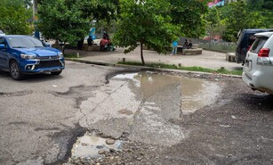 Entre hoyos y agua acumulada: as&iacute; transitan conductores y peatones por calles del Gran Santo Domingo
