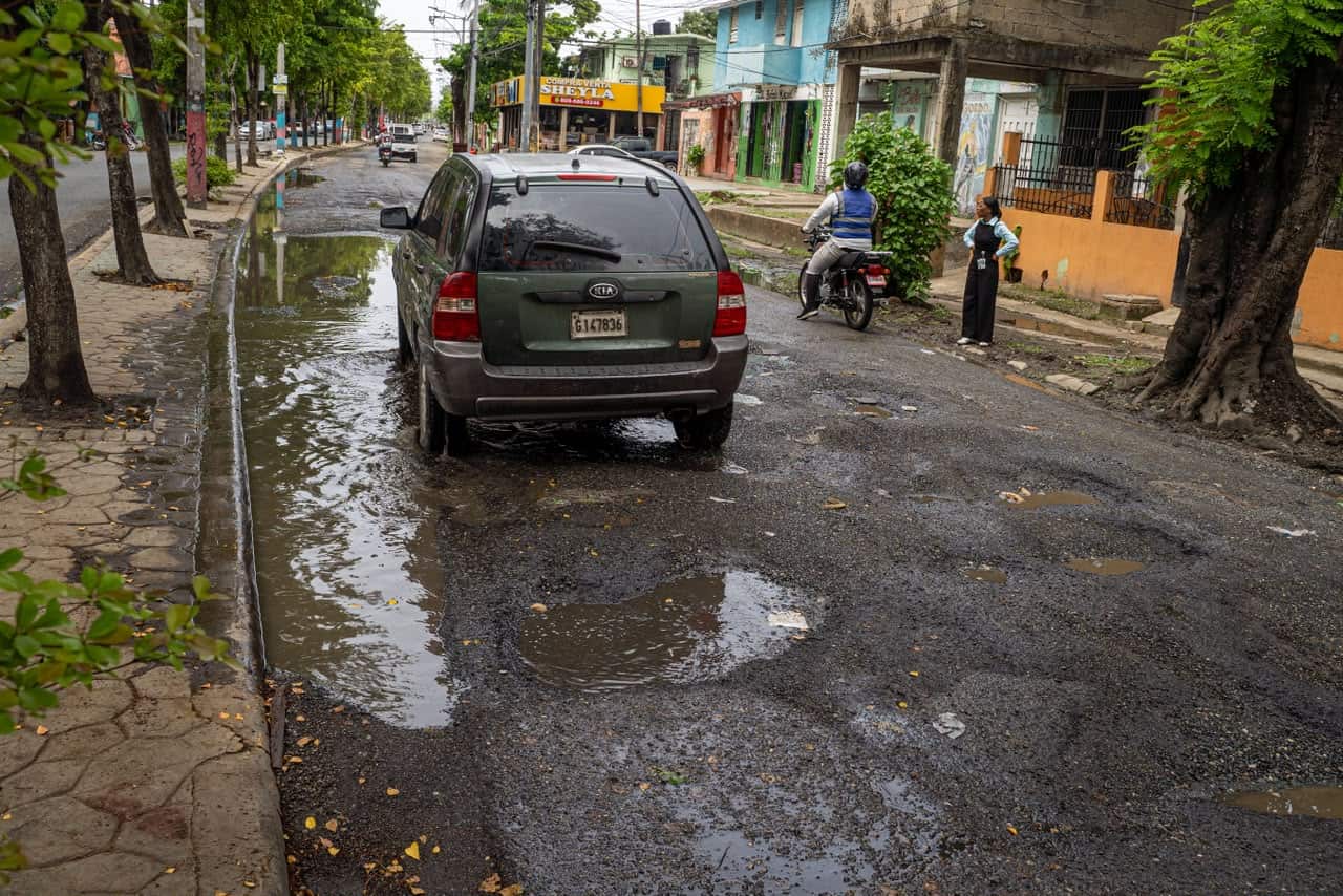 El agua acumulada oculta los baches en la avenida Francisco del Rosario Sánchez, Guachupita, Distrito Nacional, dificultando el paso de vehículos y motocicletas.