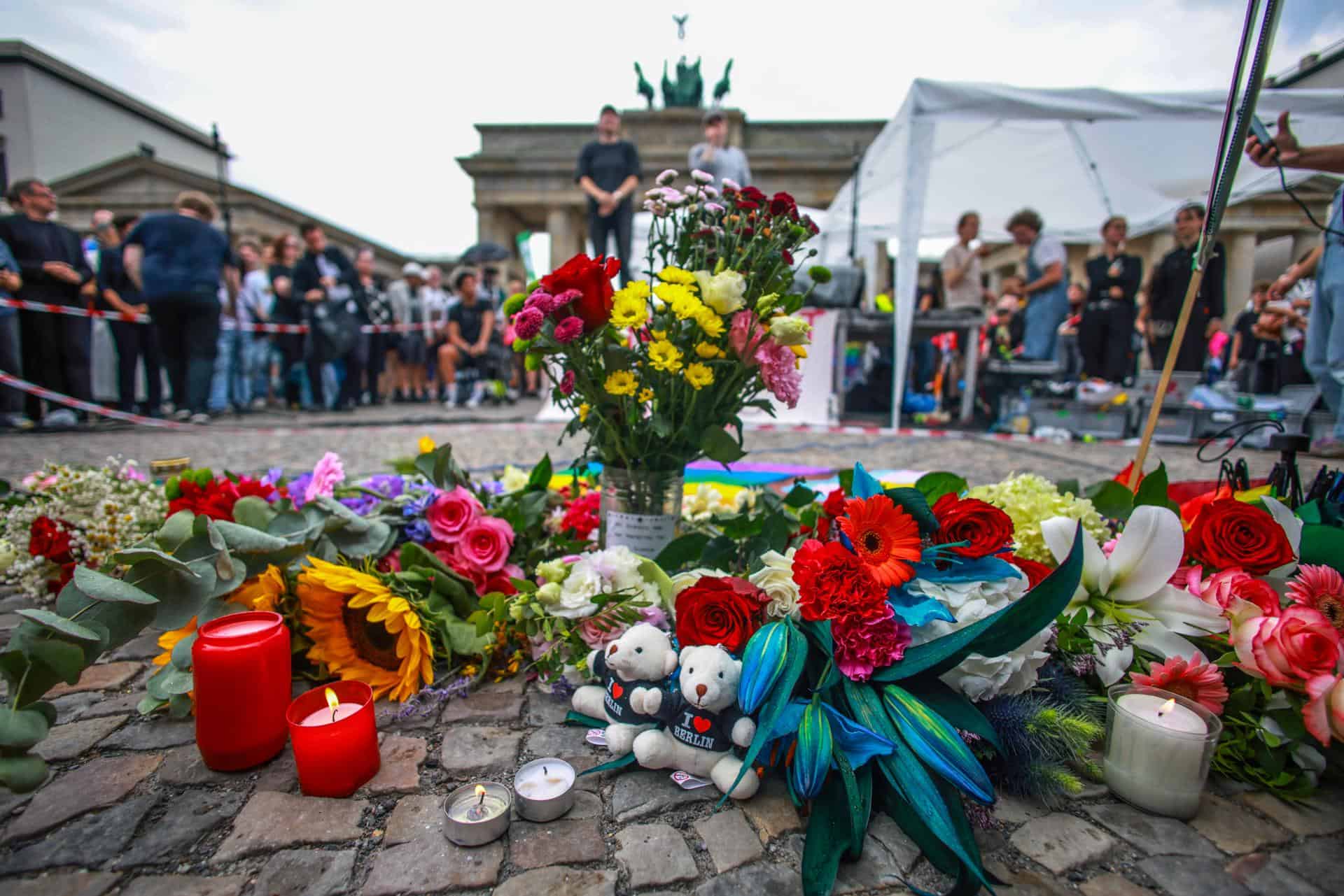 Personas guardan luto frente a la Puerta de Brandeburgo, cerca del lugar donde un vehículo arrolló a una multitud al margen del desfile del Christopher Street Day (CSD) en Berlín, Alemania, el 26 de julio de 2026.