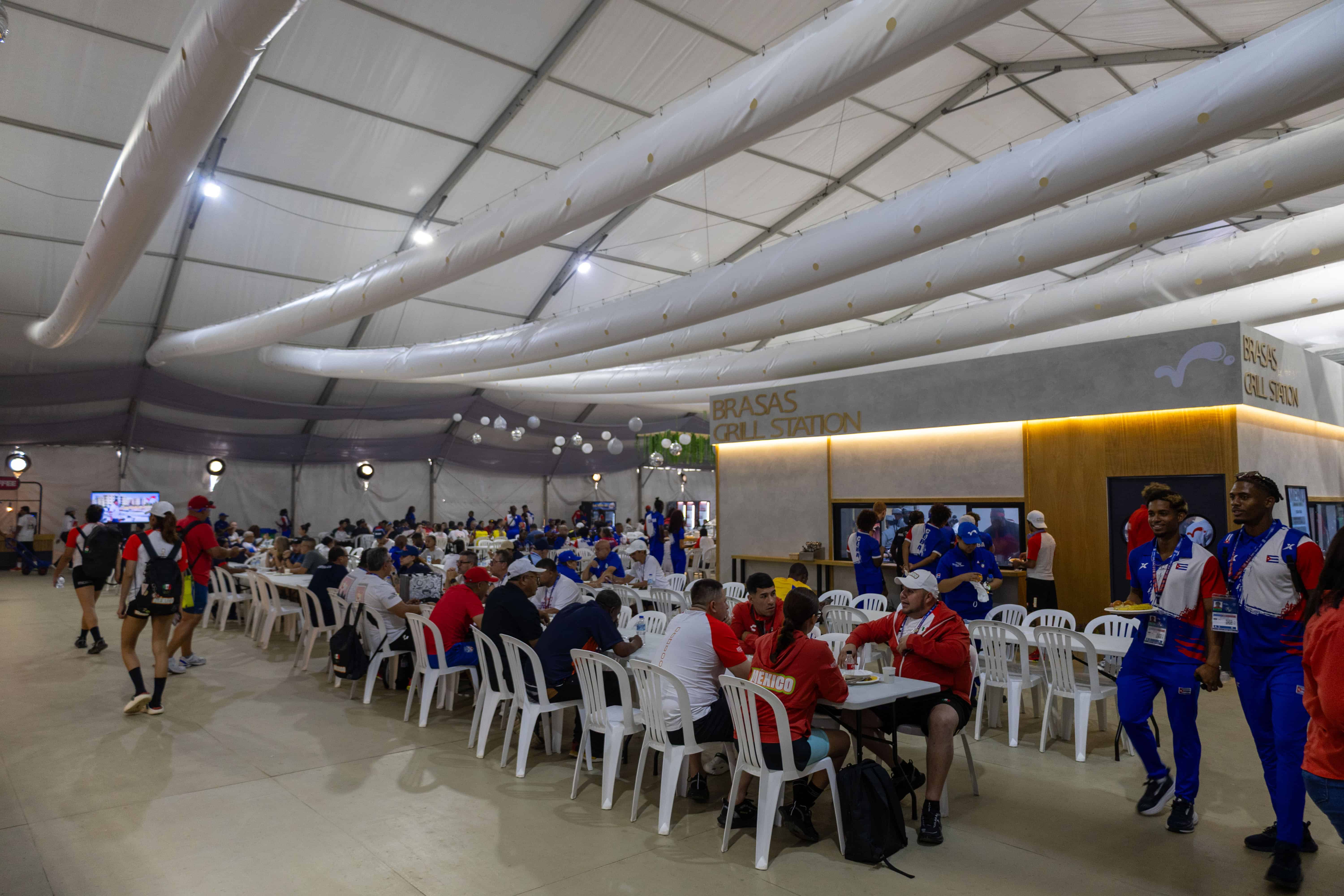 Atletas de distintas delegaciones compartiendo sus comidas en el comedor
