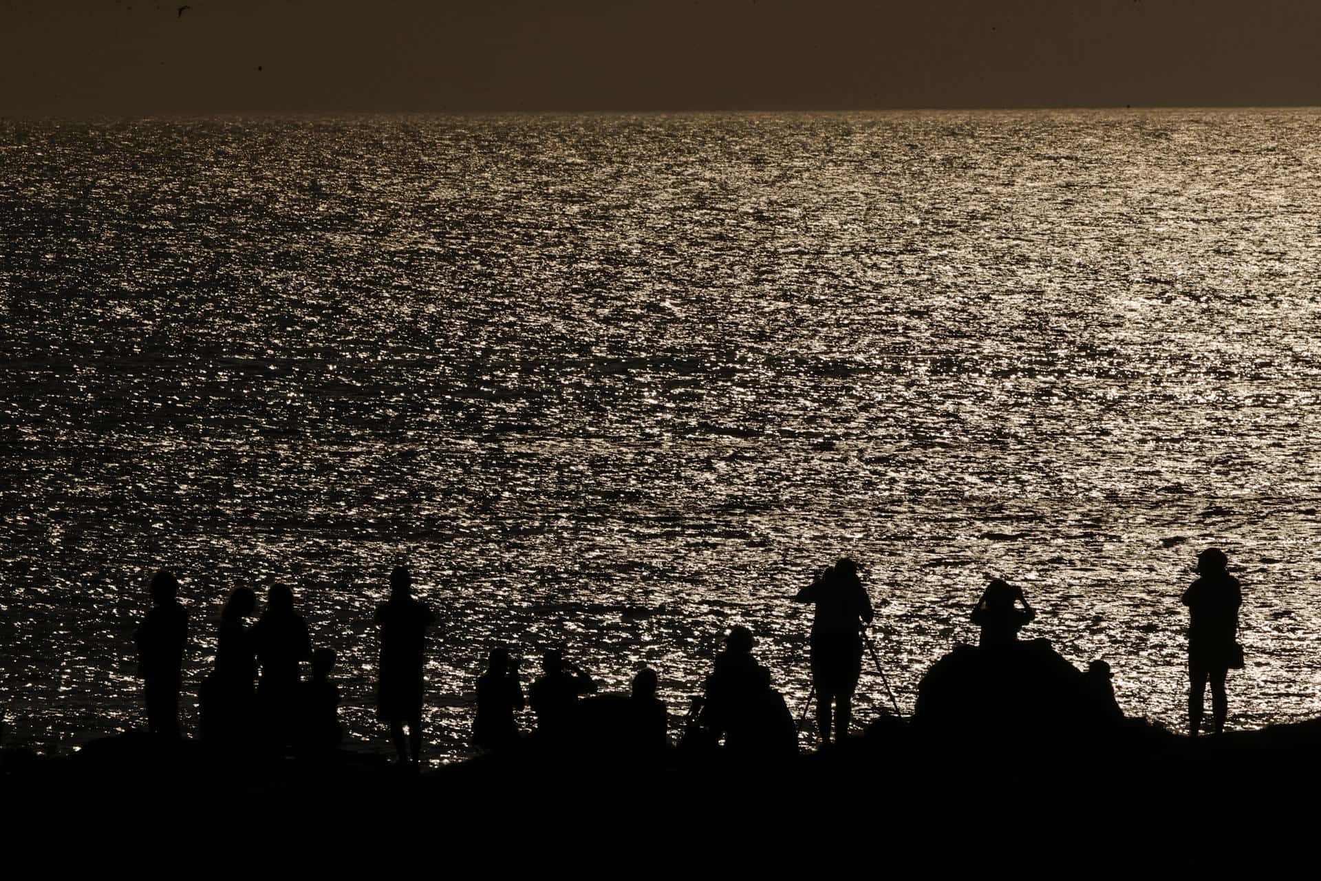 Decenas de personas aobservan el eclipse de sol visto desde la playa de Doniños en Ferrol.