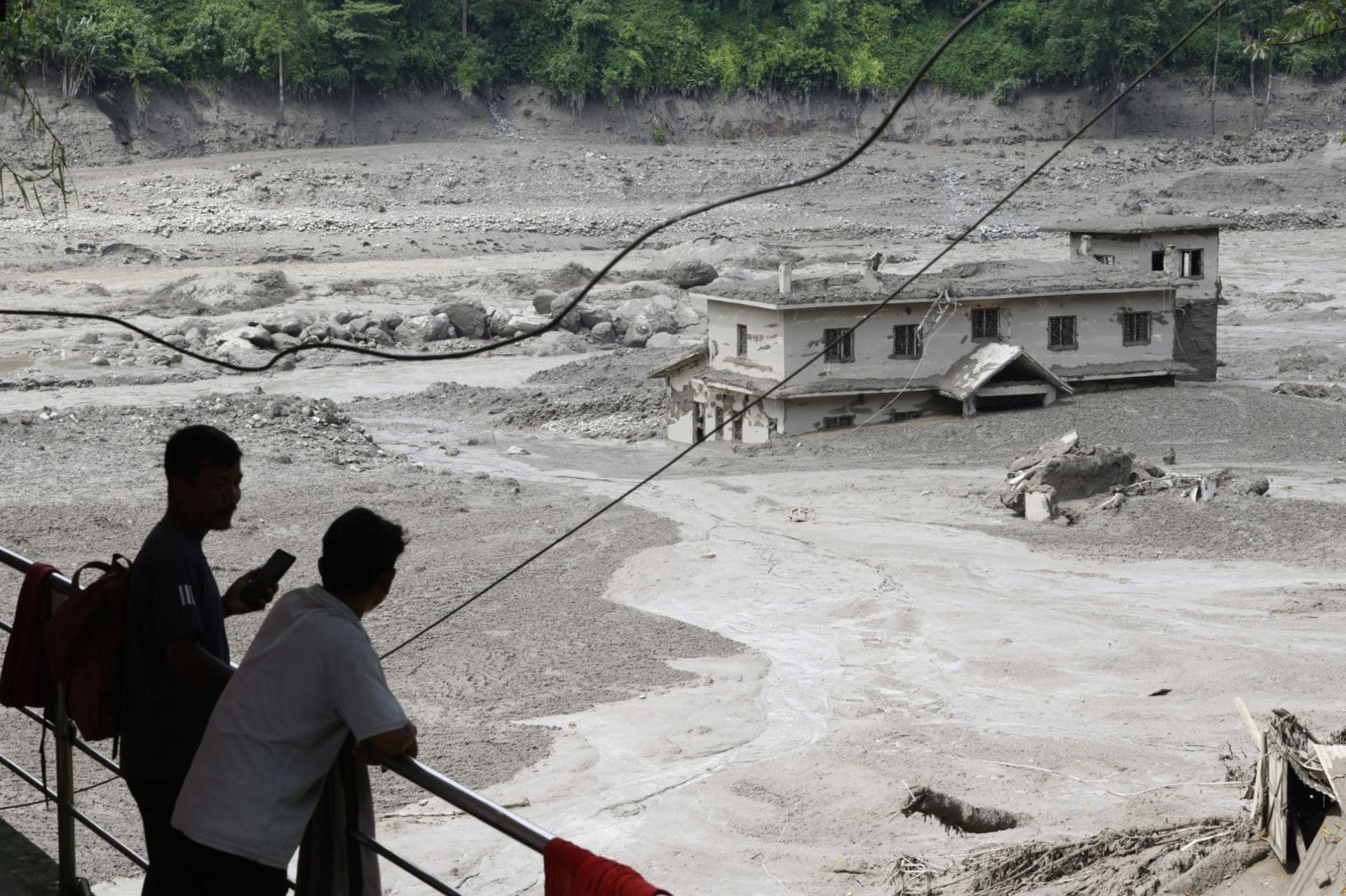 La gente observa cómo las aguas de la inundación arrasan Trishuli Bazar tras una crecida repentina, en el distrito de Nuwakot, Nepal.