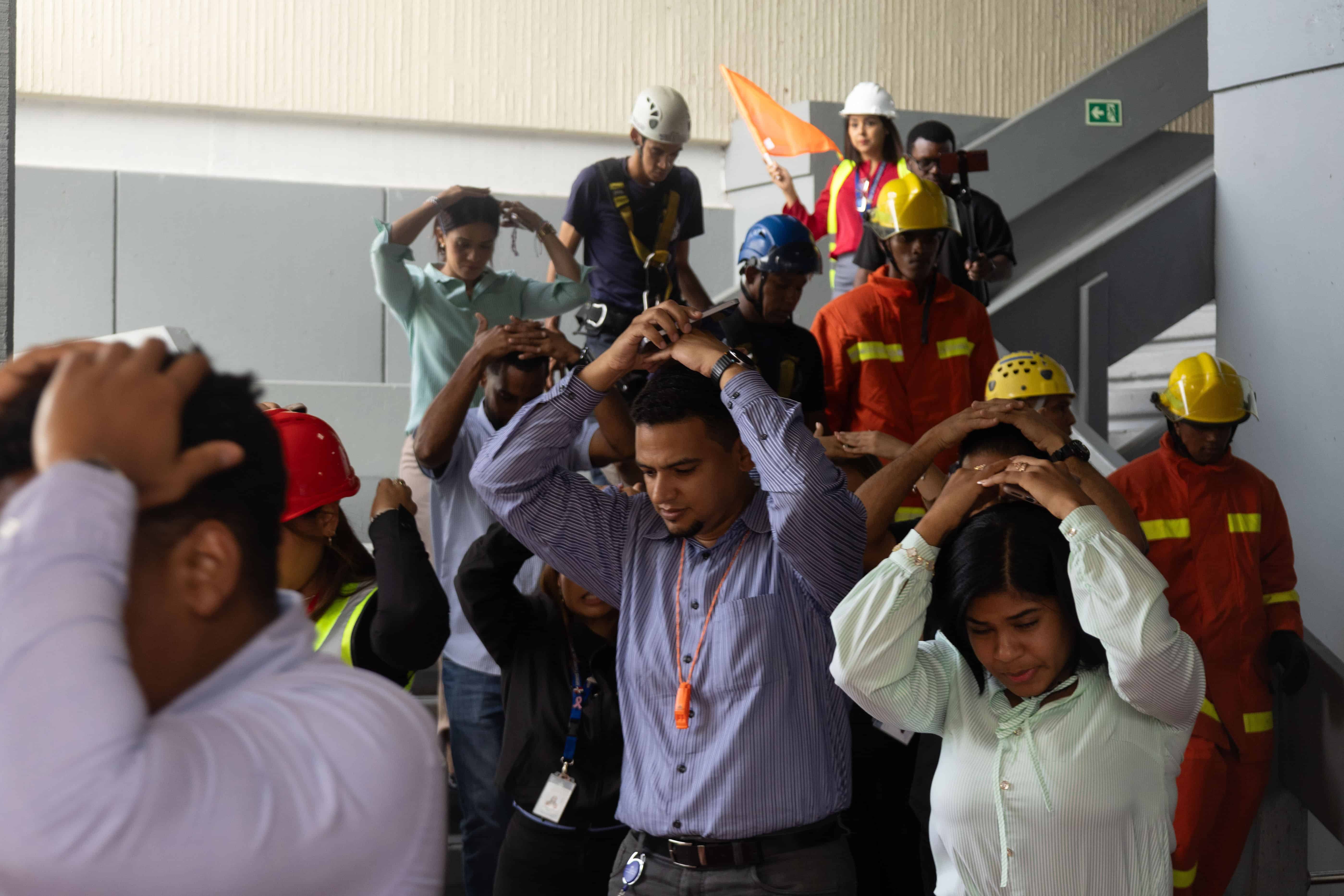 Grupo de empleados en el edificio de Oficinas Gubernamentales Juan Pablo Duarte, conocido como El Huacal bajan las escaleras en el momento del simulacro.