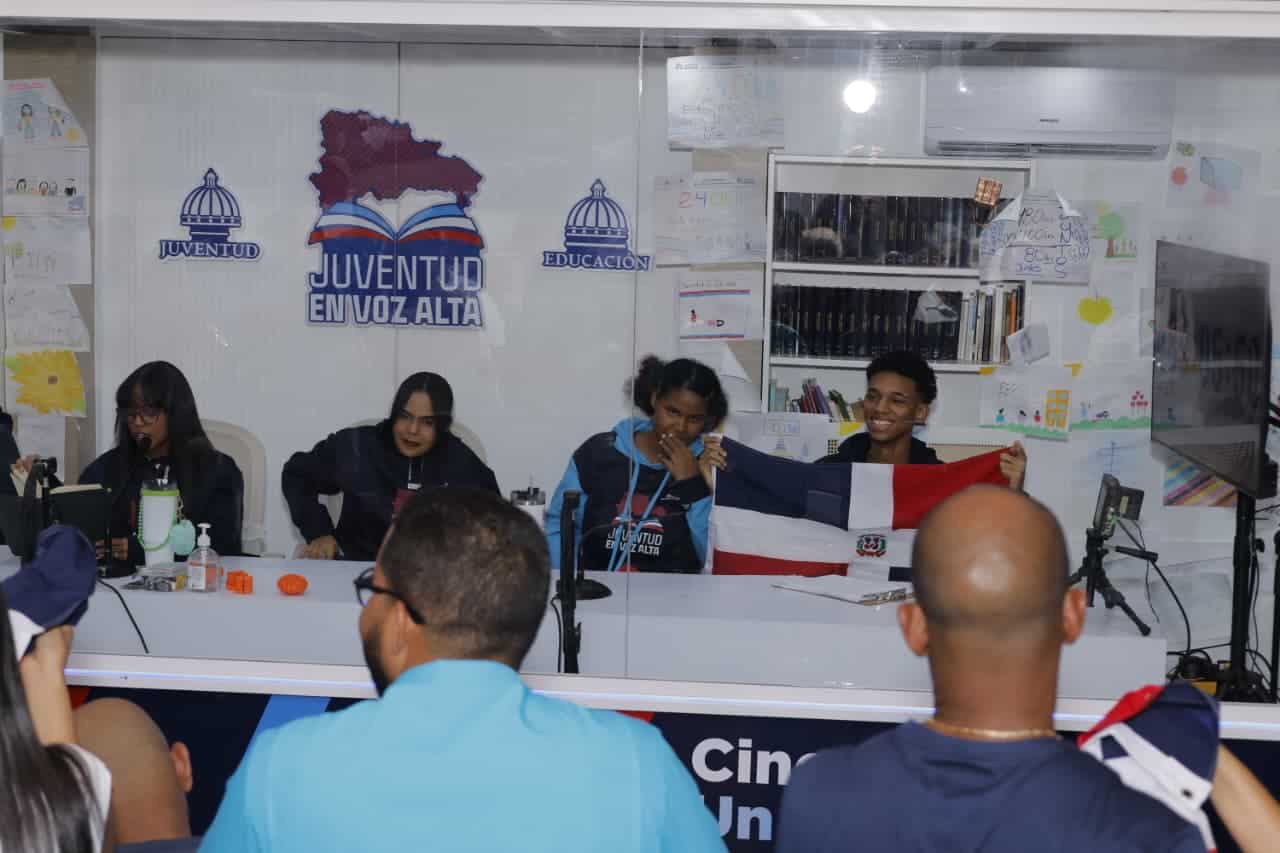 Jóvenes en lectura en voz alta acompañados de varias personas.