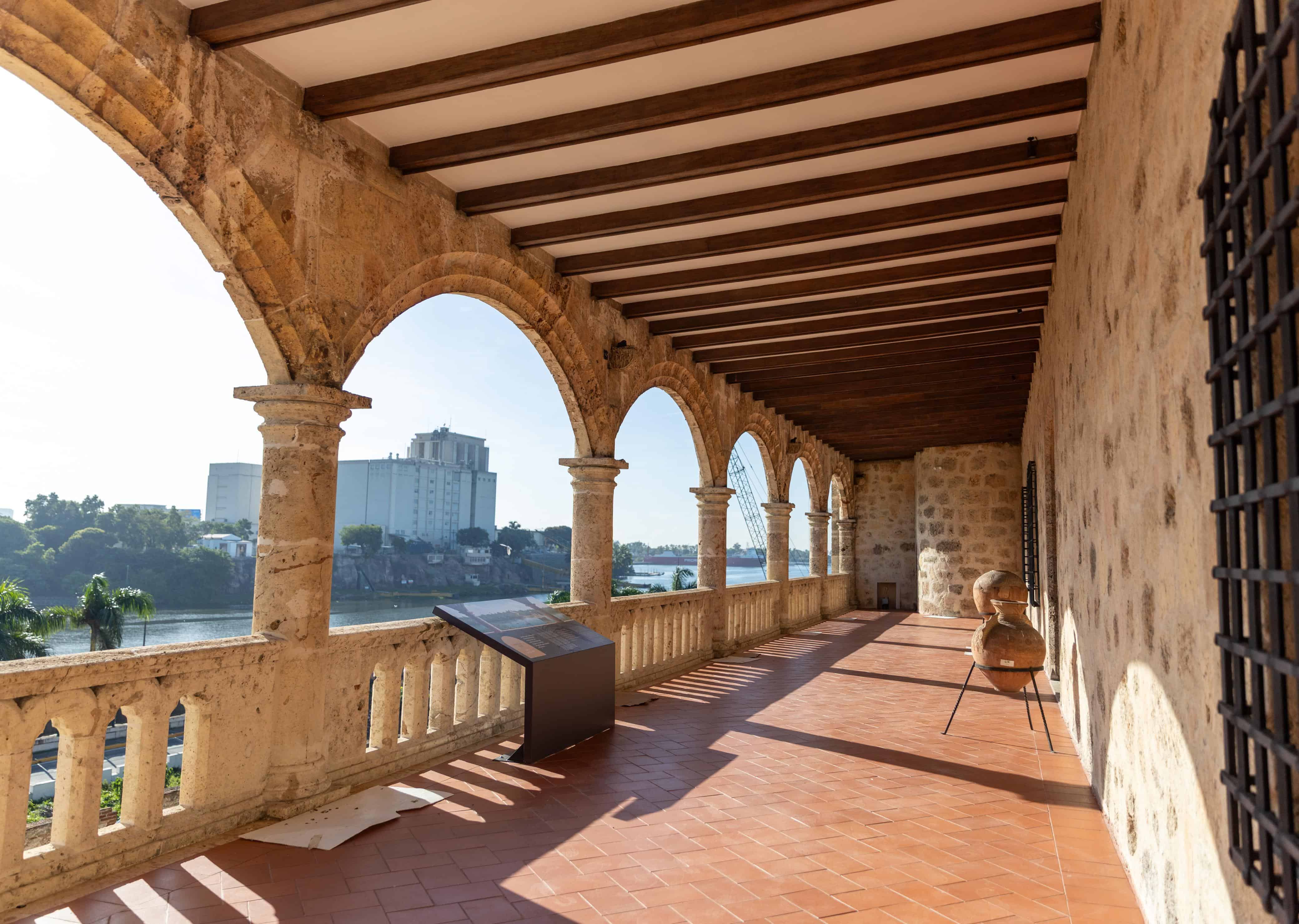 Vista exterior del corredor superior porticado del palacio, caracterizado por sus arcos de medio punto en piedra coralina y su vista panor&aacute;mica hacia el r&iacute;o Ozama.