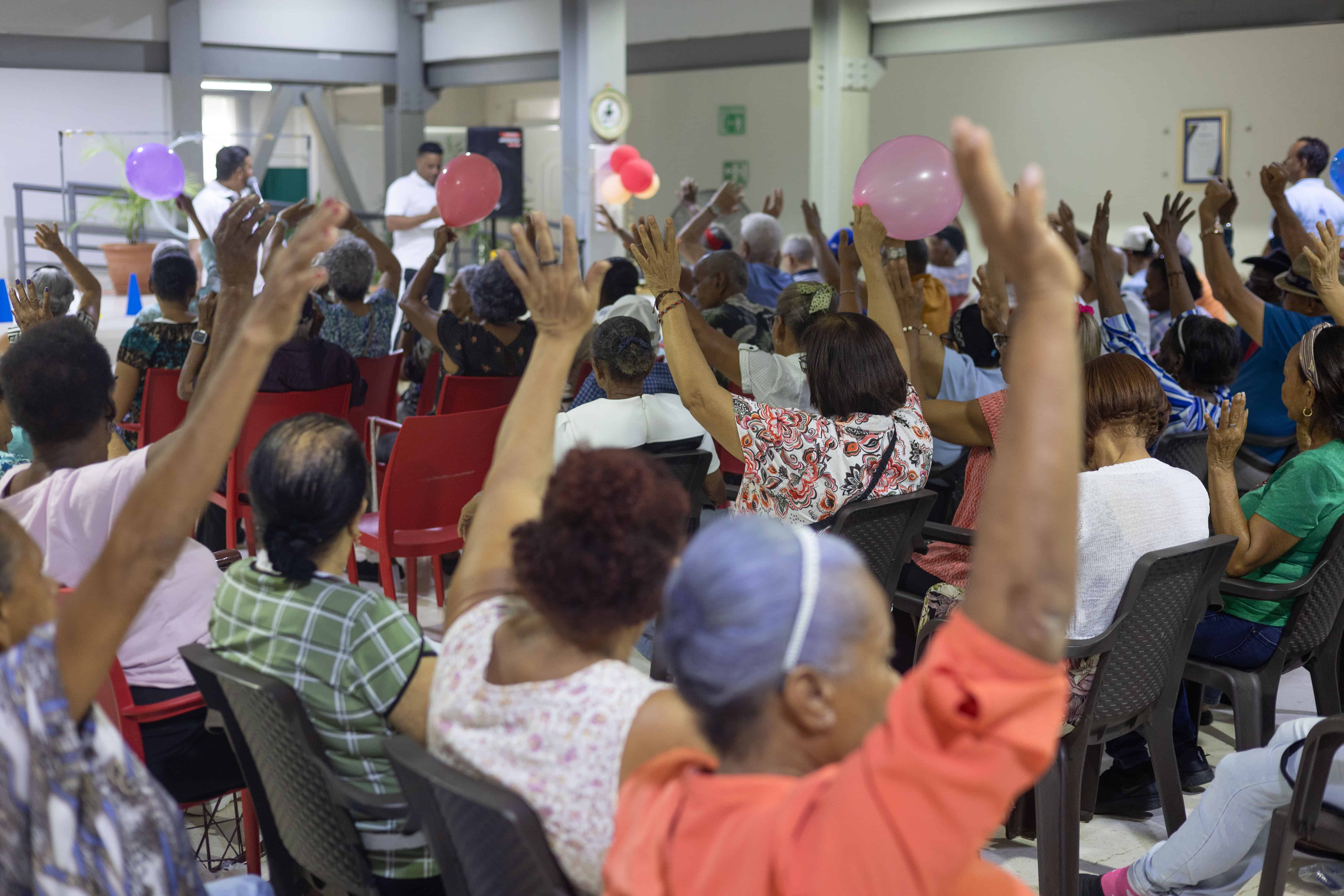 Usuarios del centro levantan las manos mientras participan con entusiasmo en una de las actividades.