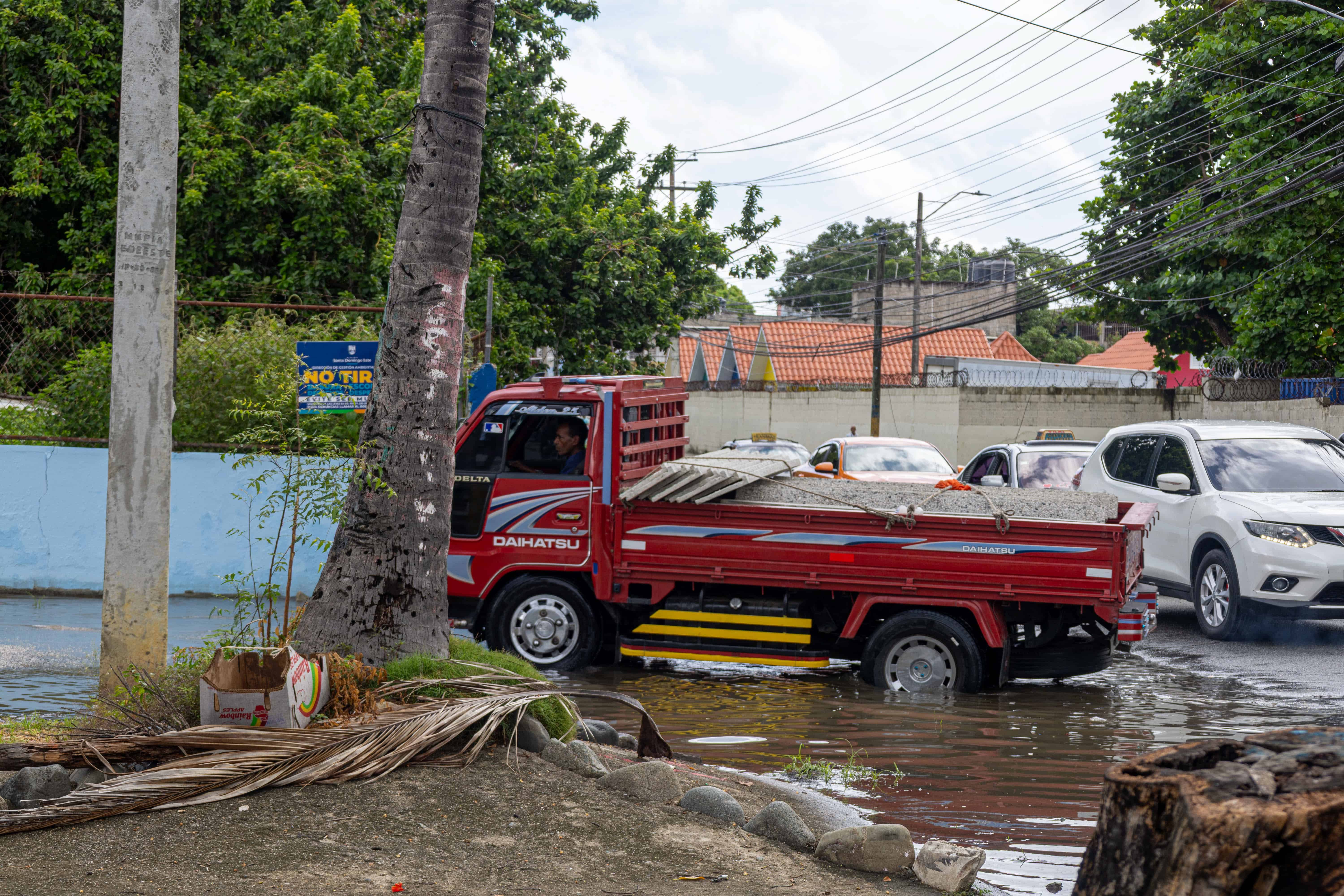 Un cami&oacute;n atraviesa con precauci&oacute;n el tramo con agua acumulada en la calle A del sector Los Mameyes.