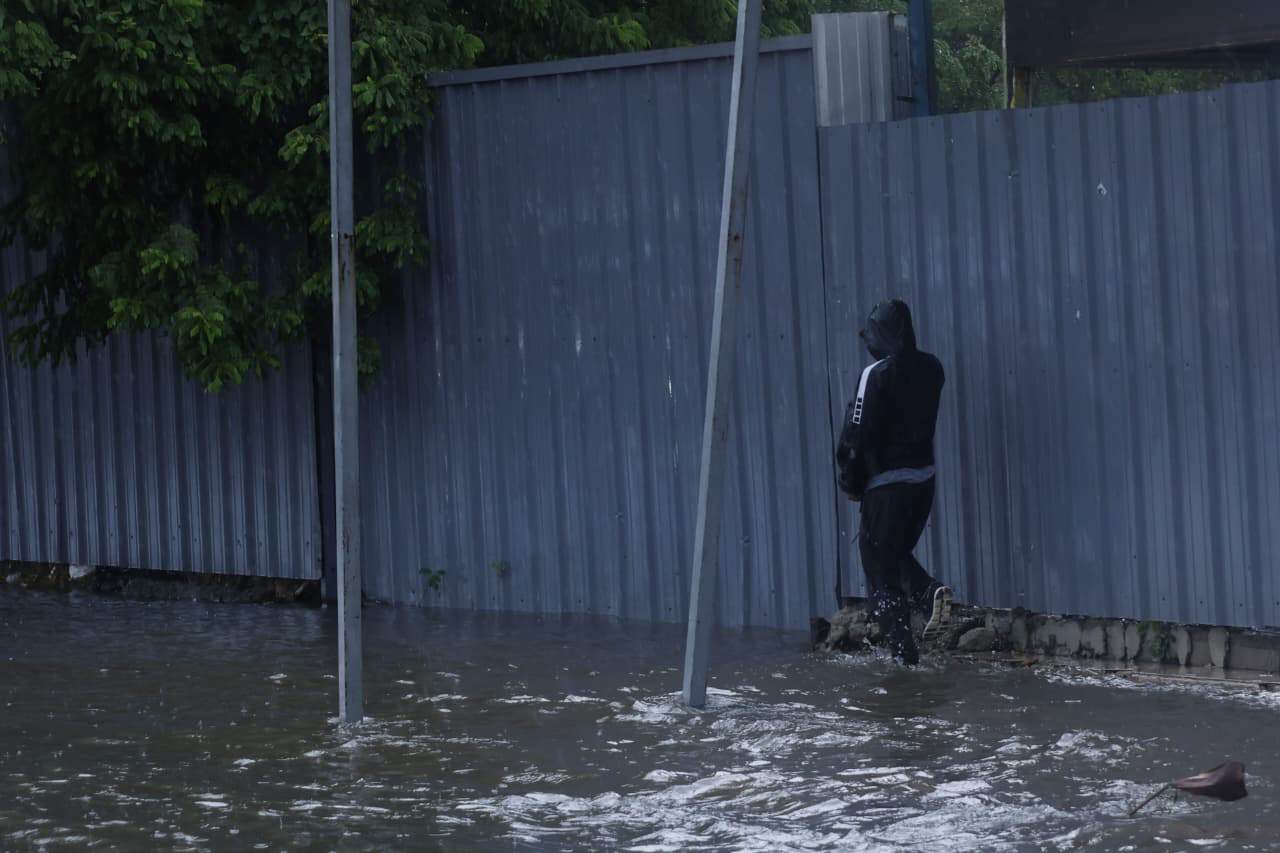 Un hombre camina por una acera anegada debido a las lluvias en el Gran Santo Domingo.