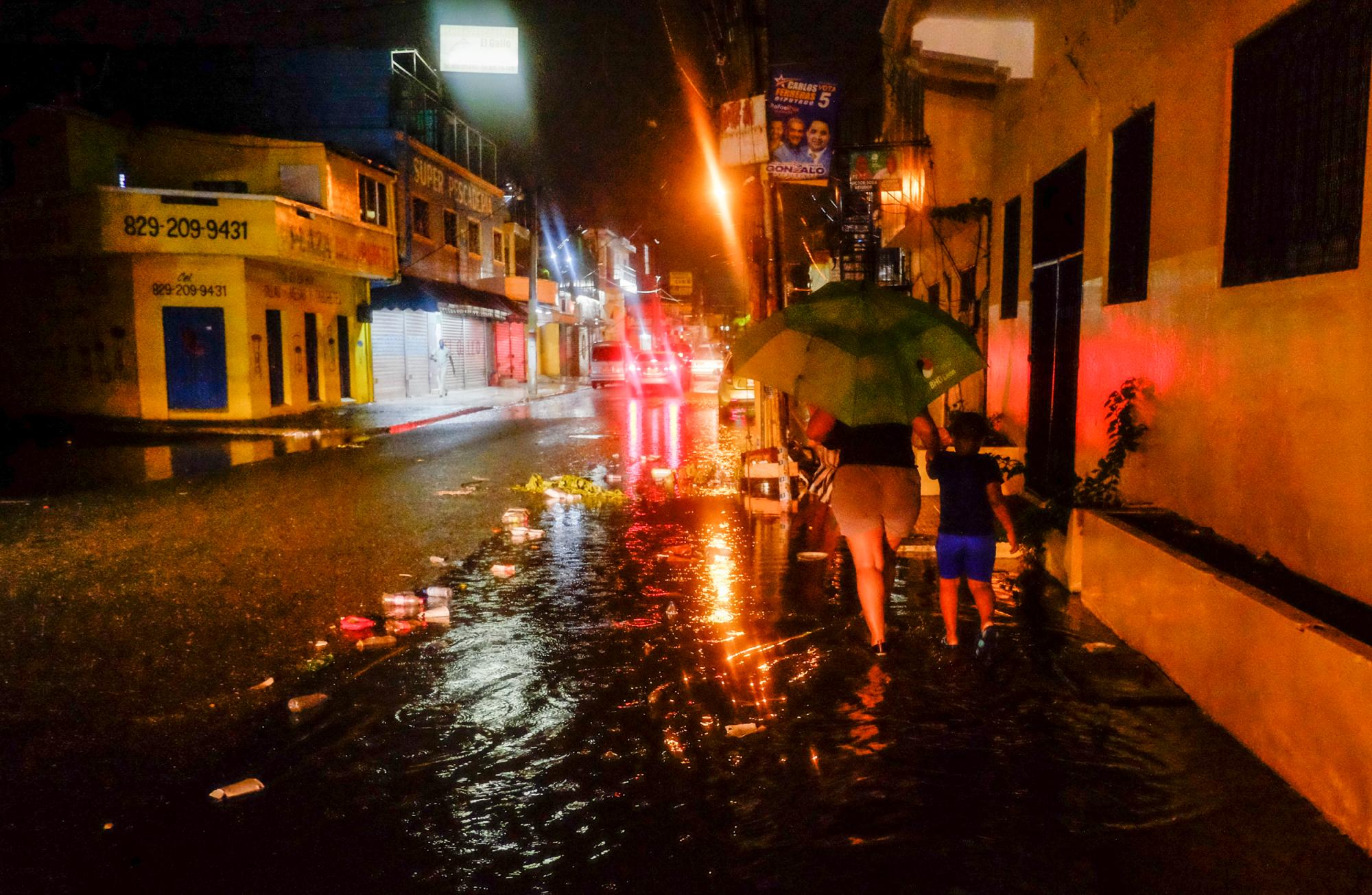 Santo Domingo, RD: una mujer que lleva de la mano a un niño, camina entre un charco de agua, en  la calle Peña Batlle de Villa Juana. Pese a los esfuerzos de autoridades, cada vez que caen fuertes lluvias la ciudad se inunda
