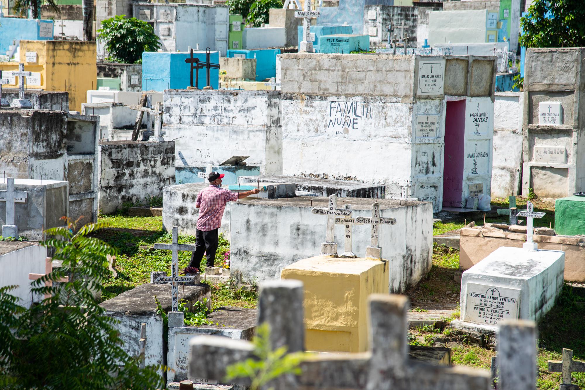 Un hombre da una mano de pintura a una de las tumbas en el Cementerio de Cristo Rey, durante la celebración del Día de los Fieles Difuntos. (Fotos: Dania Acevedo)