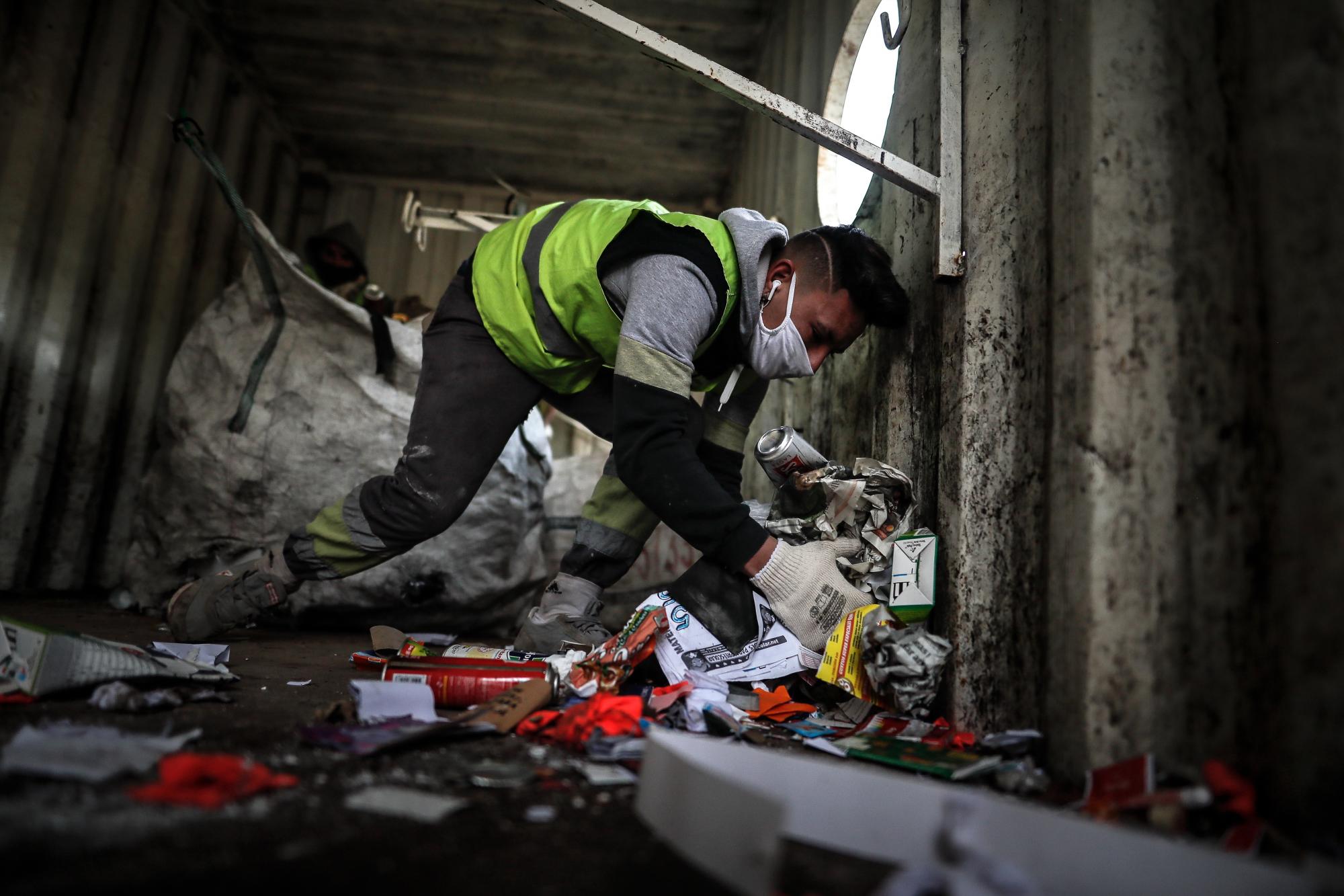 Un miembro de la cooperativa 18 de abril busca materiales en un contenedor de basura de la ciudad de Buenos Aires (EFE/ Juan Ignacio Roncoroni)